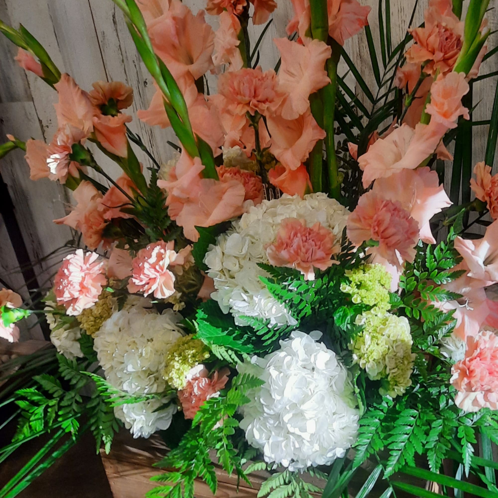 Peach carnations and white hydrangeas arranged with fern greenery