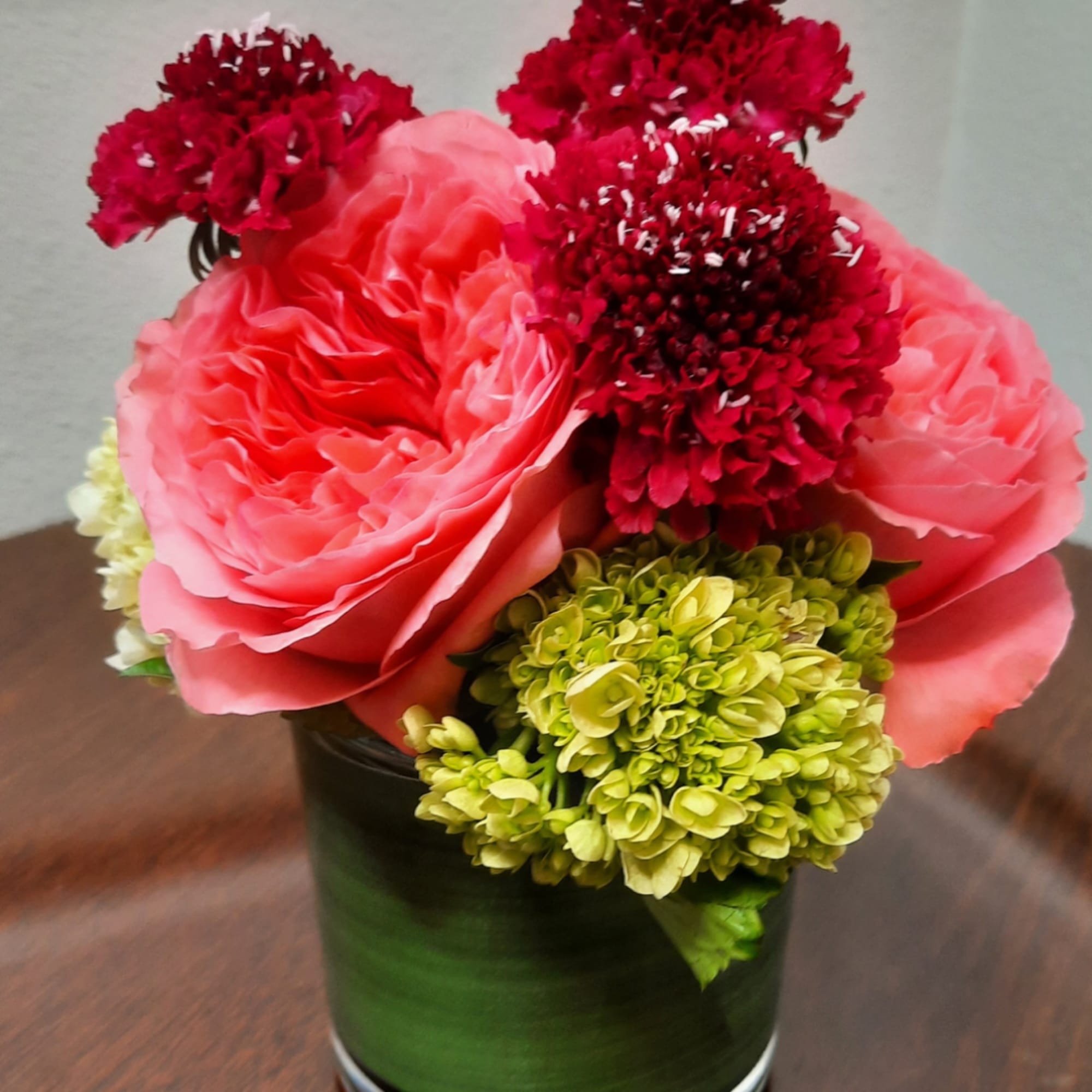 Pink and red floral arrangement in a green vase