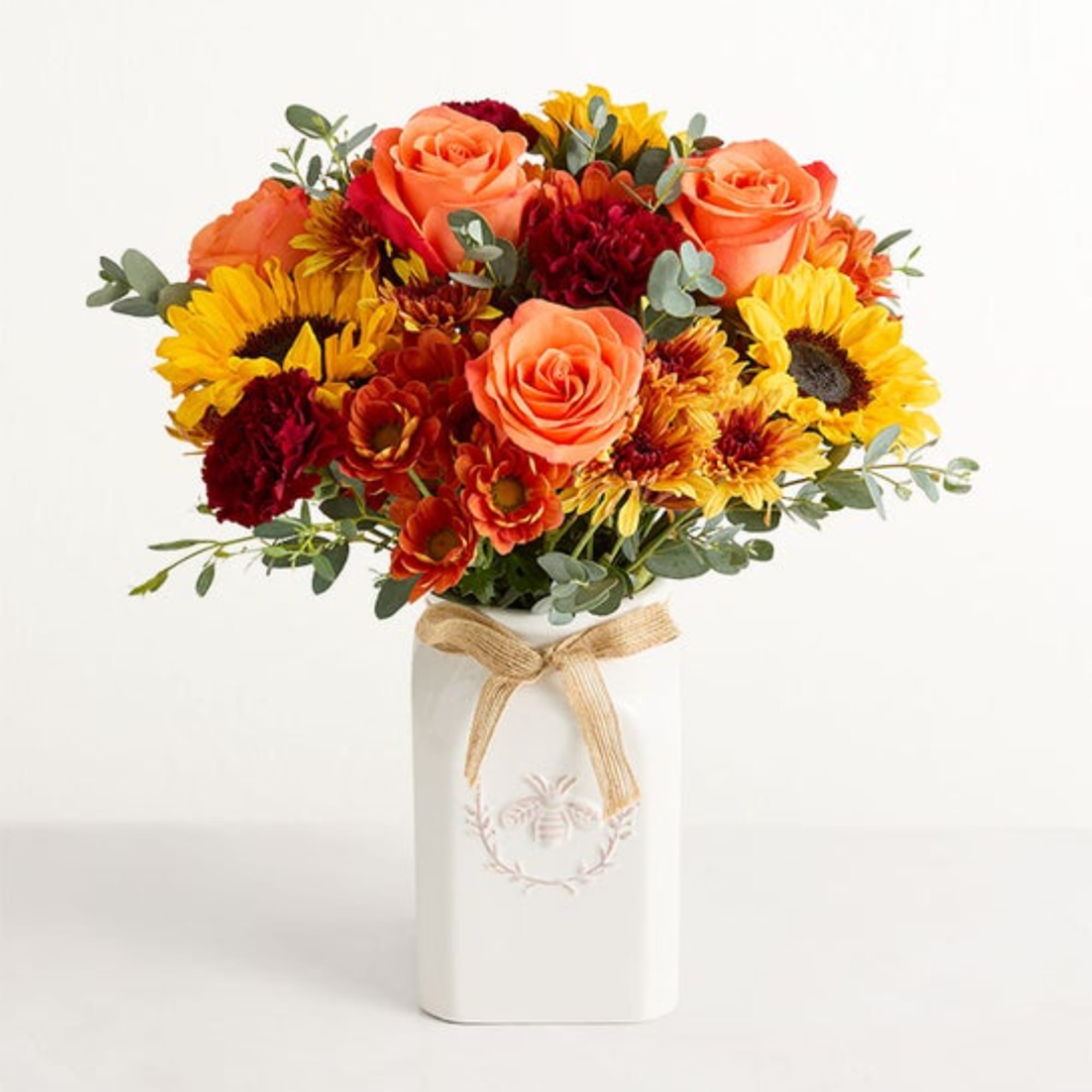 Bouquet of orange roses and yellow sunflowers in a white vase