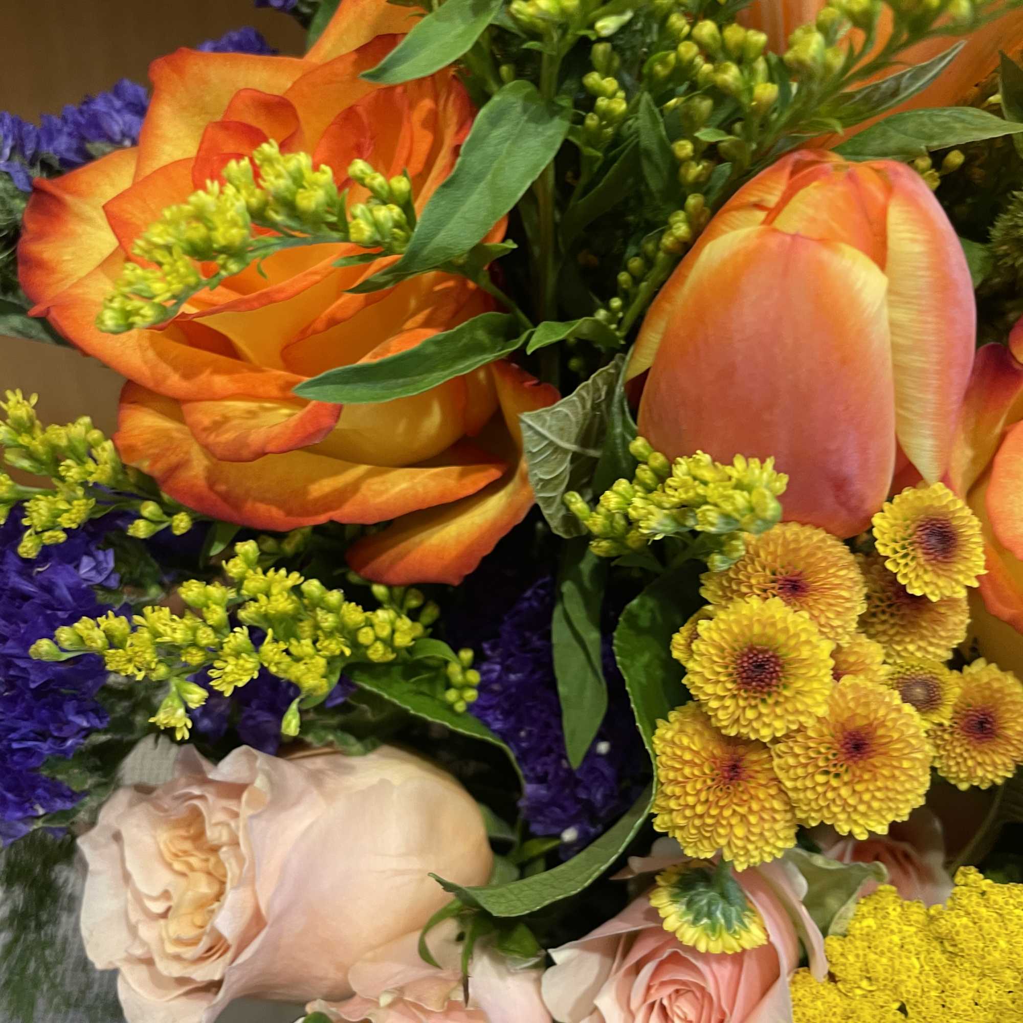 Bouquet of orange tulips, peach roses, and yellow button mums