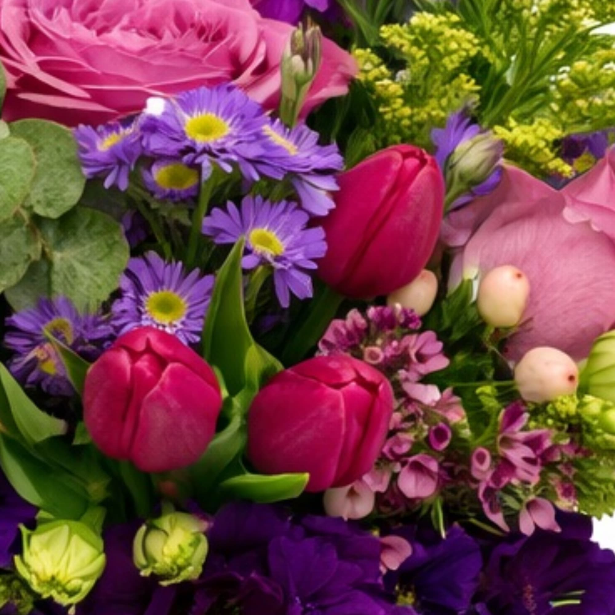 Bouquet of pink tulips and purple flowers in a glass vase