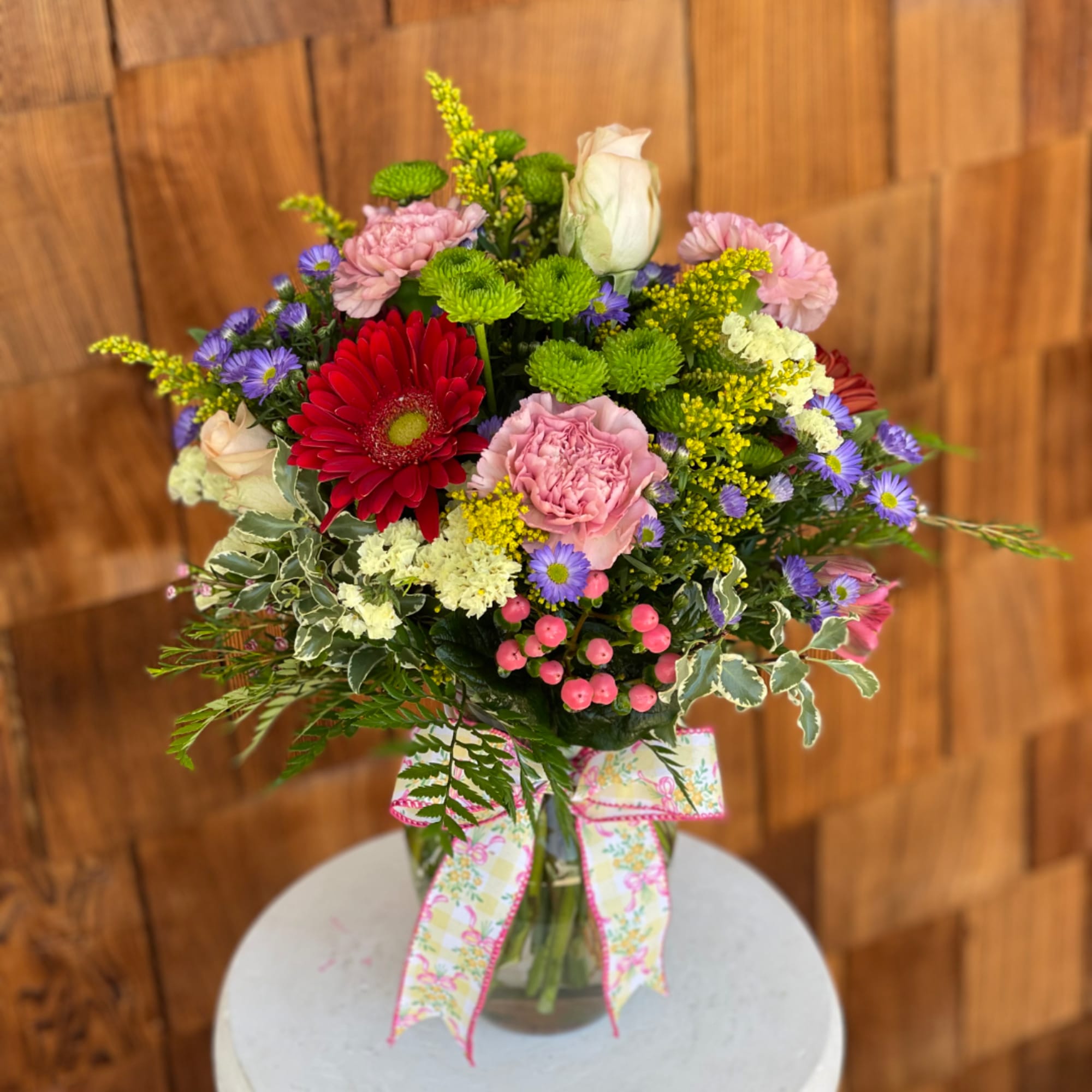 Mixed bouquet in a glass vase with a patterned ribbon bow