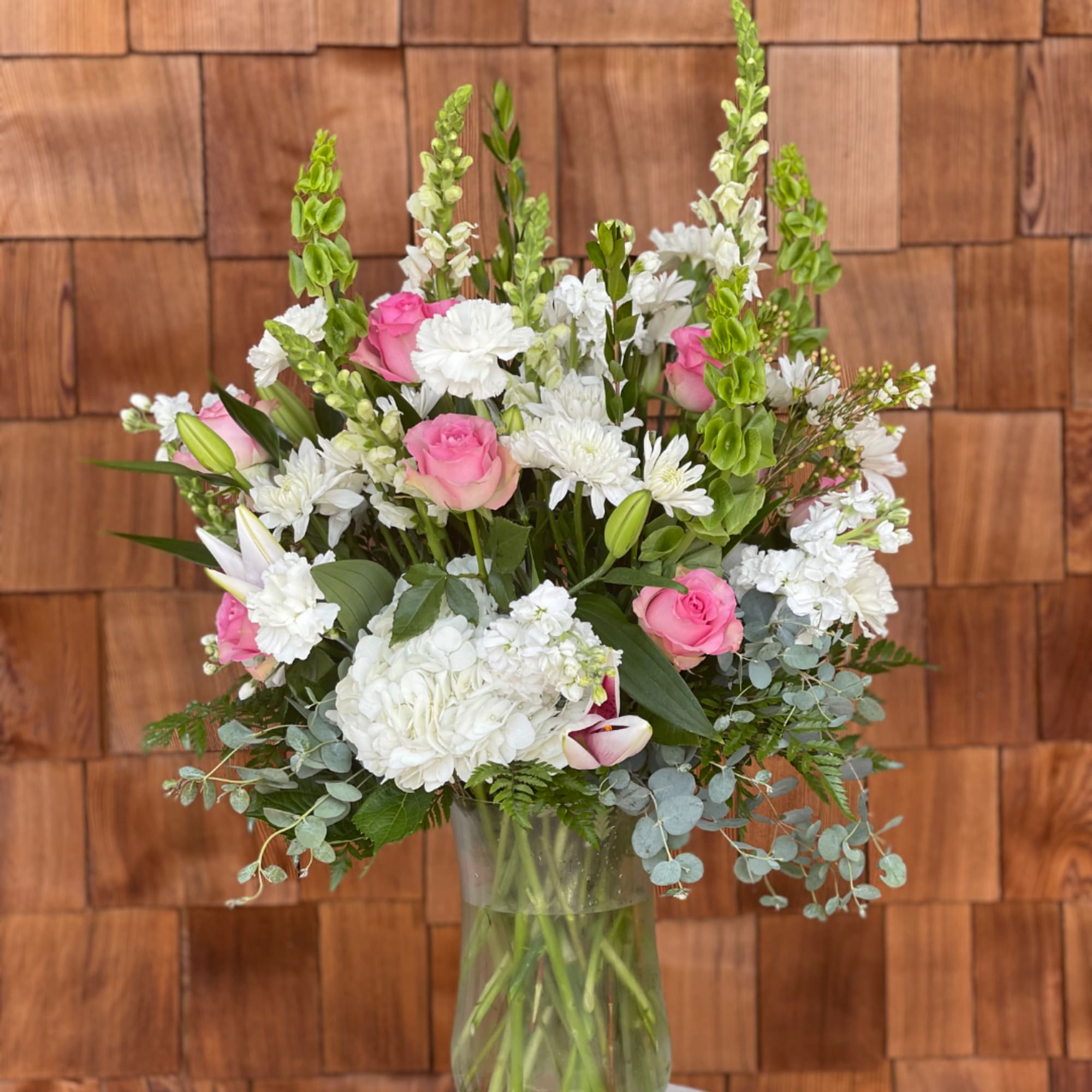 Pink roses and white flowers arranged in a clear glass vase