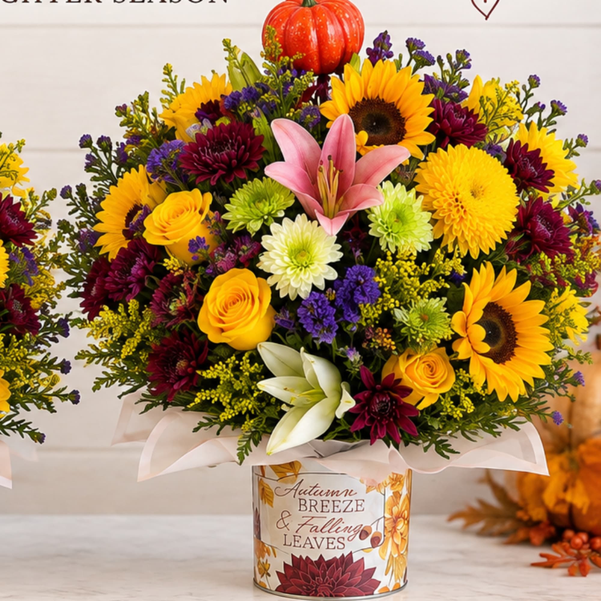 Autumn bouquet with sunflowers, roses, lilies, and mums in a decorated tin container