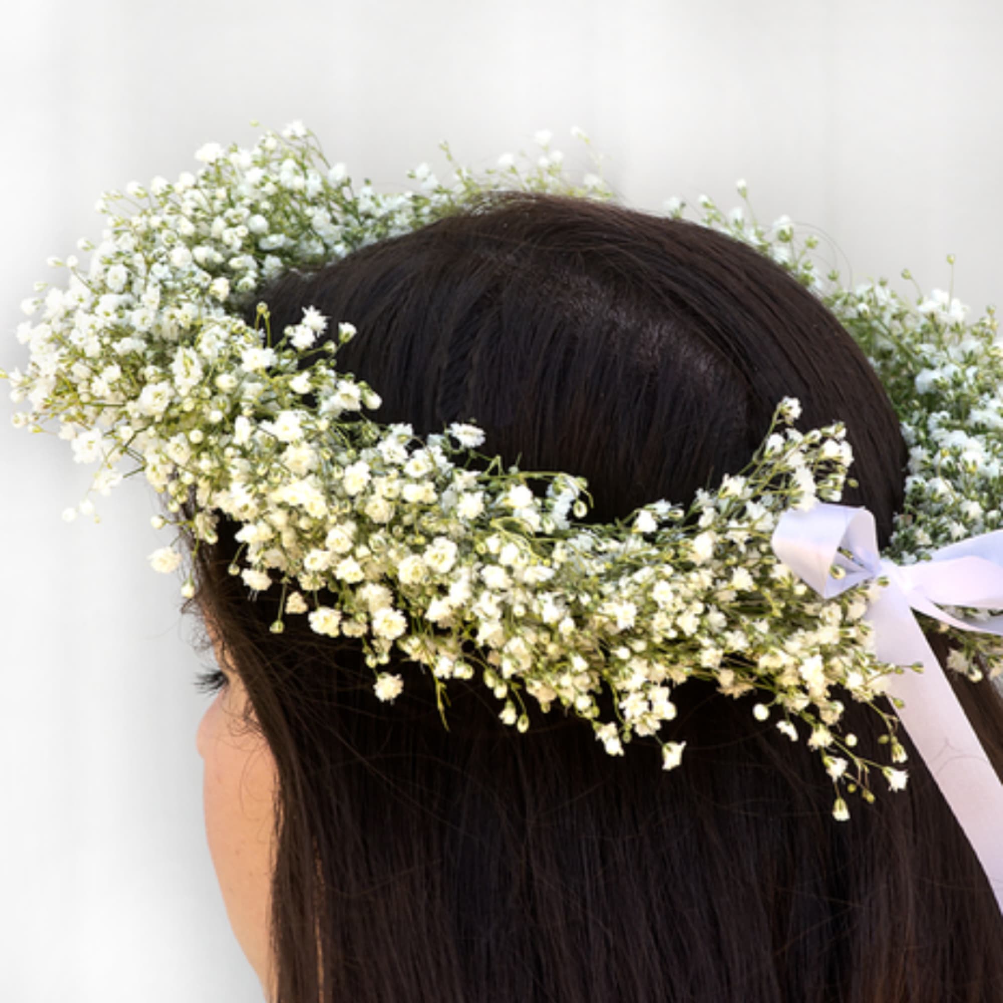 White baby's breath flower crown on a person's head with a ribbon tie