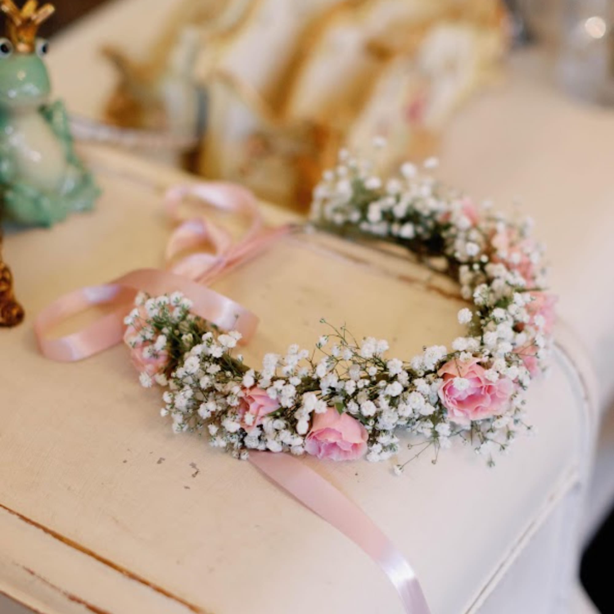 Pink flower crown with baby's breath and ribbon on a table