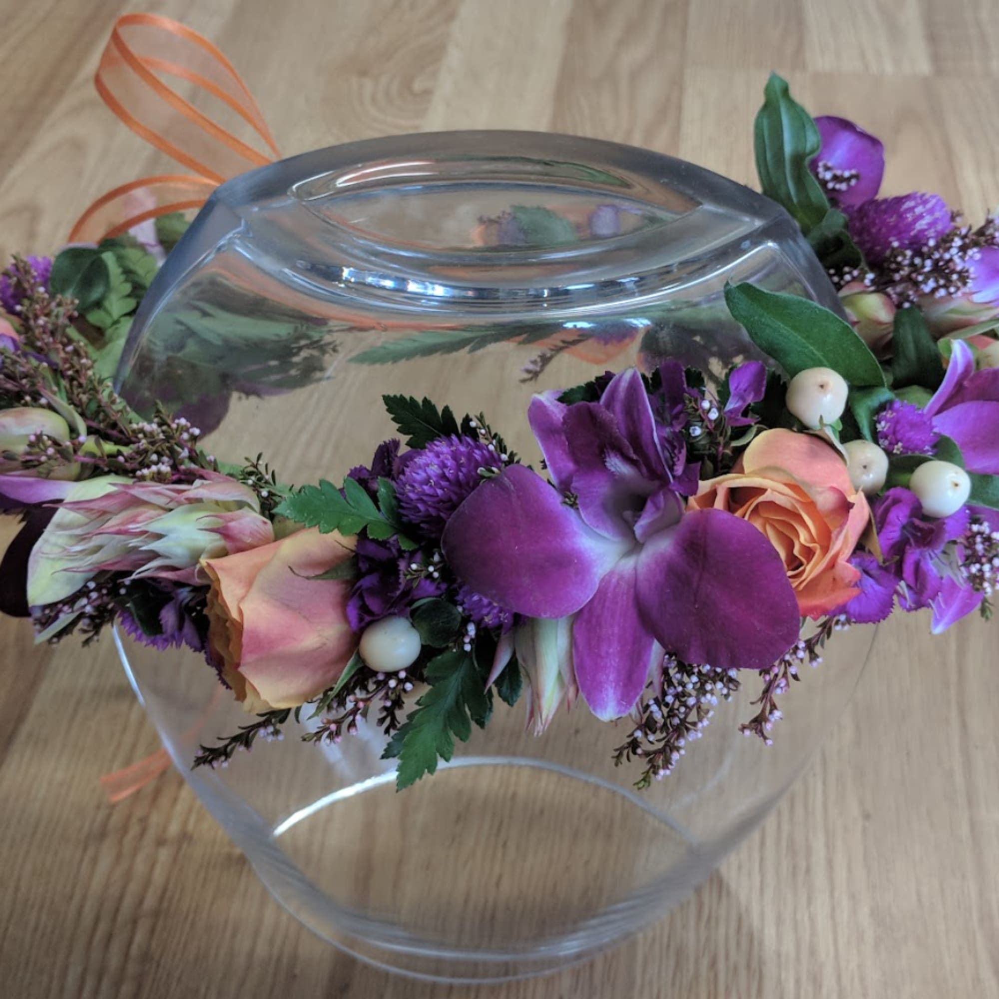 Purple and peach floral arrangement draped over a clear glass bowl