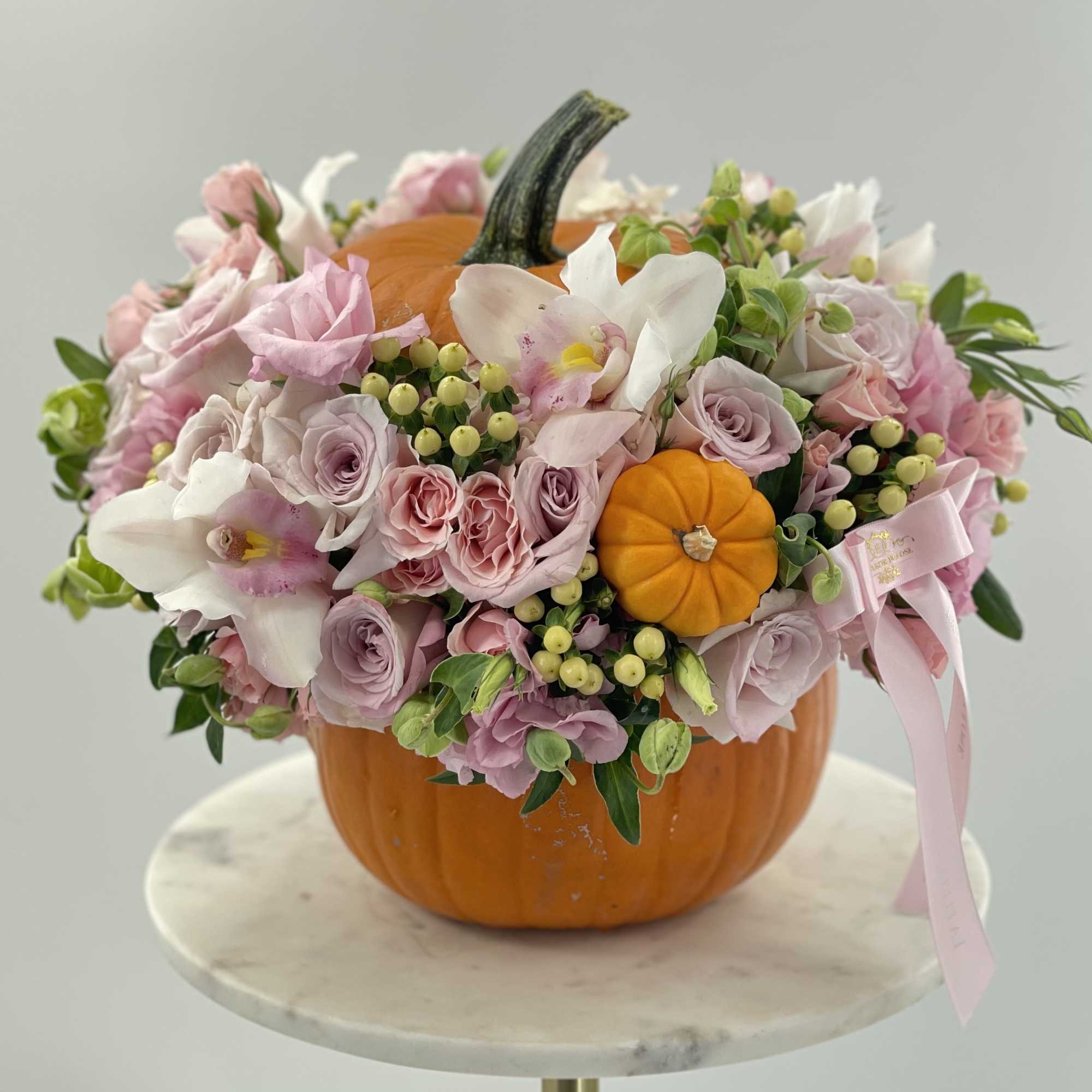 Classic orange pumpkin with an arrangement of fresh pastel flowers