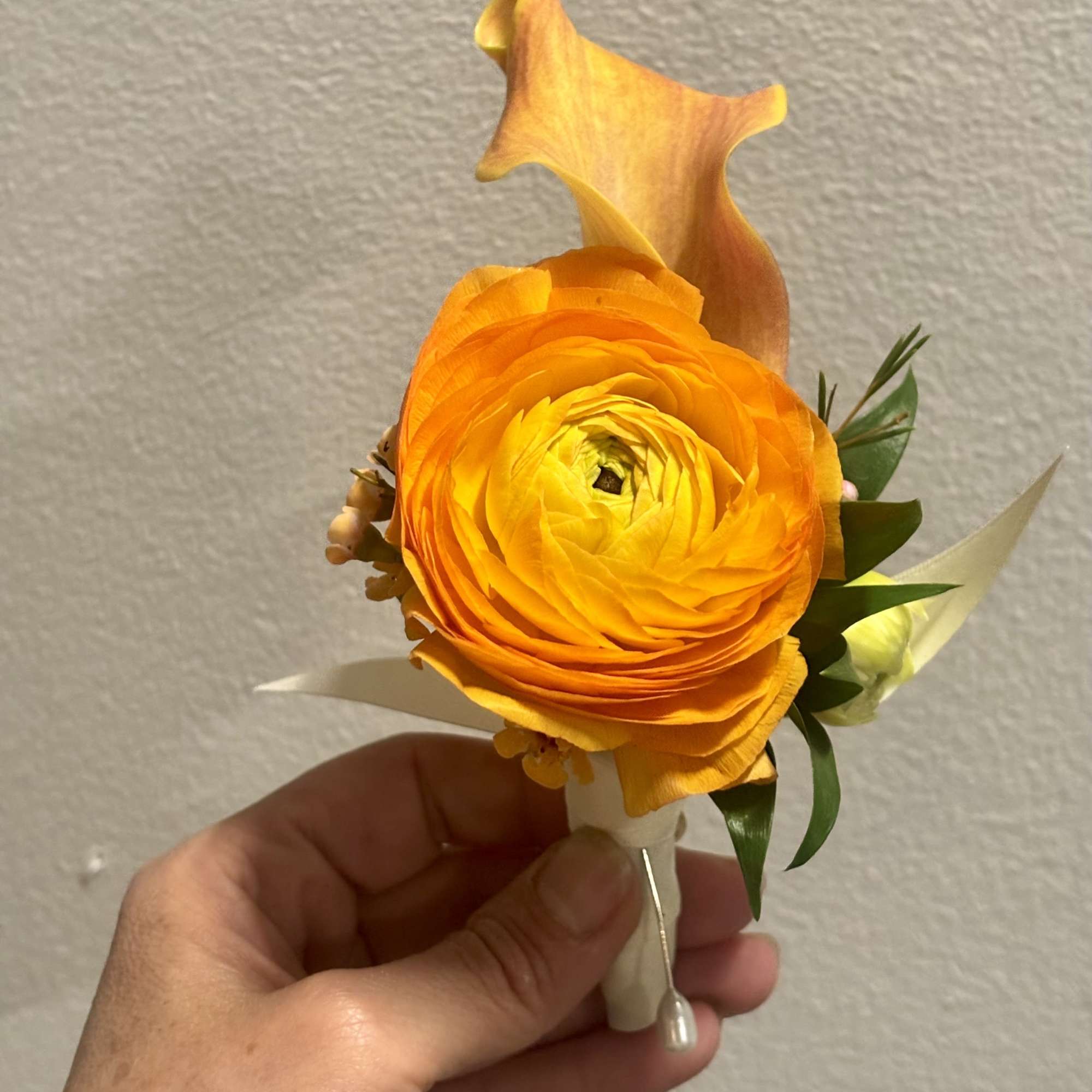Orange ranunculus boutonniere with a calla lily accent