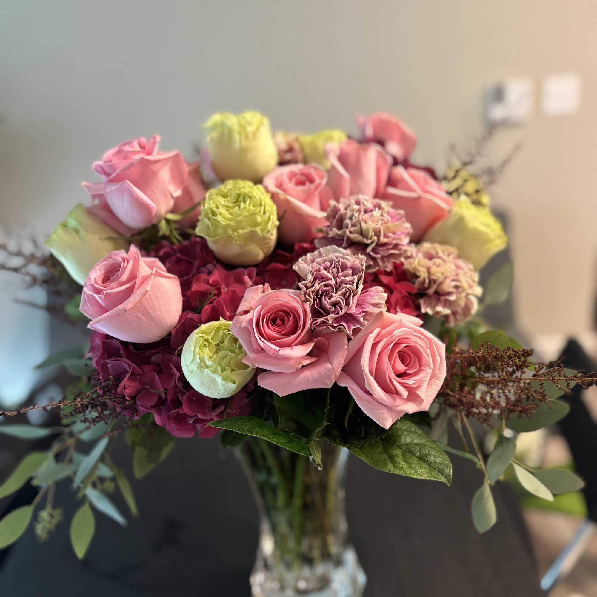 Pink roses and carnations arranged in a clear glass vase