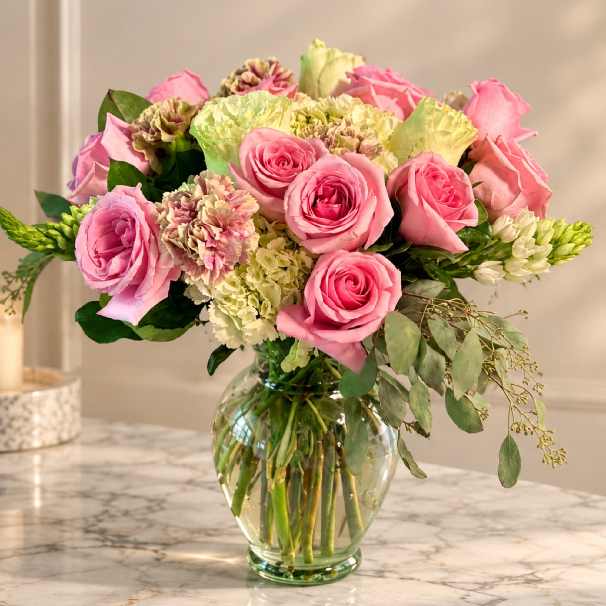 Pink roses and carnations arranged in a clear glass vase