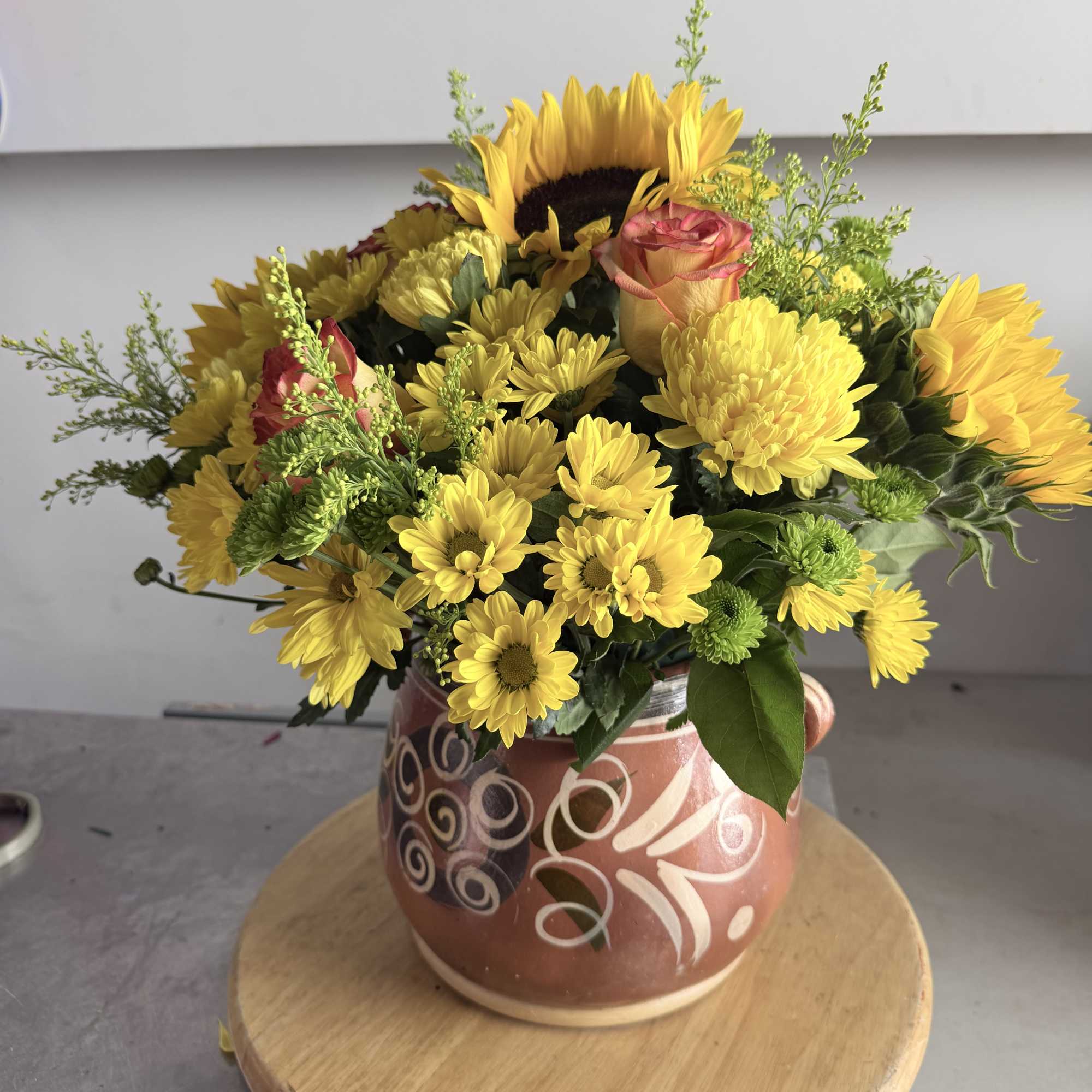 Yellow mixed flower arrangement in a patterned ceramic pot