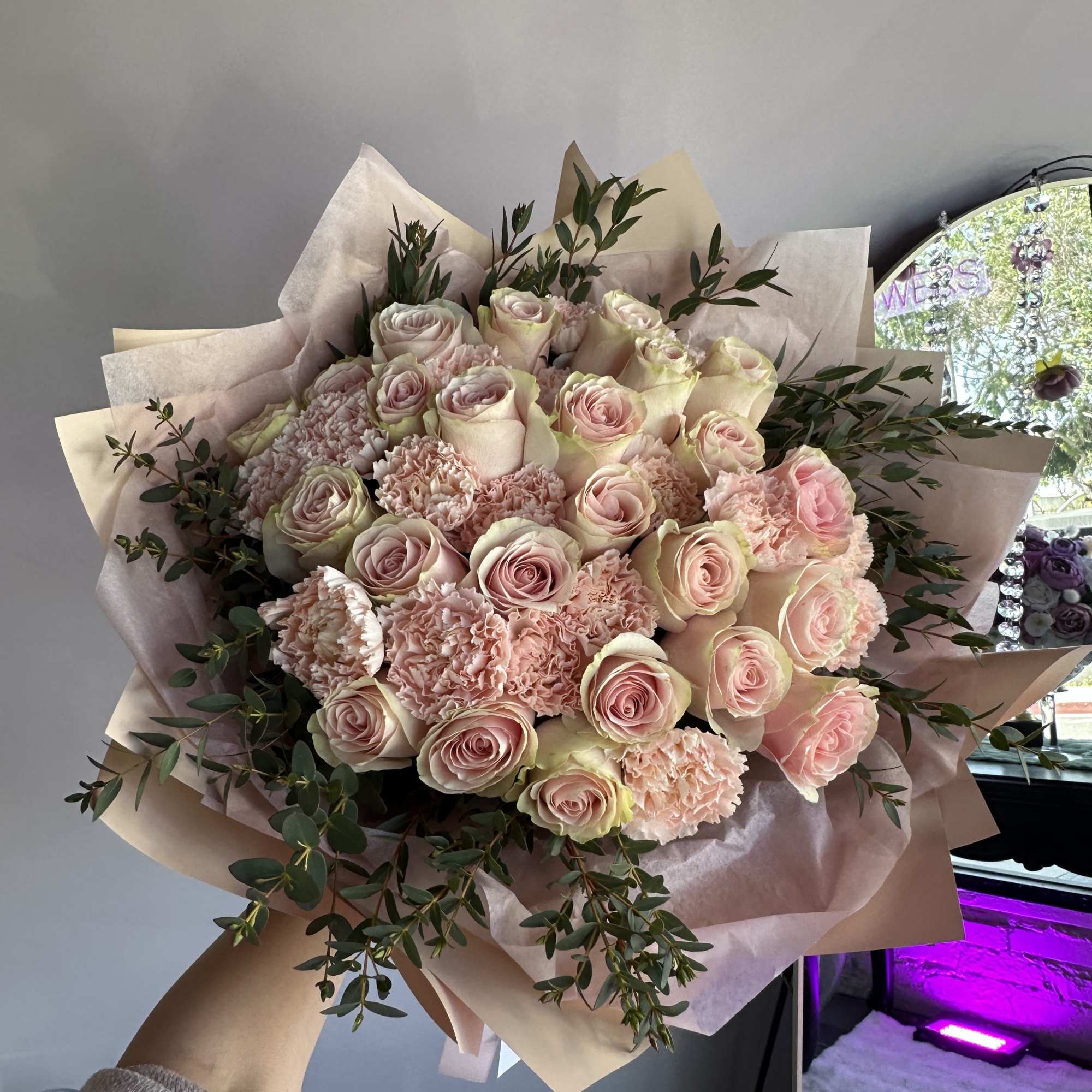 Large hand-tied bouquet of pale pink roses and carnations wrapped in soft blush paper