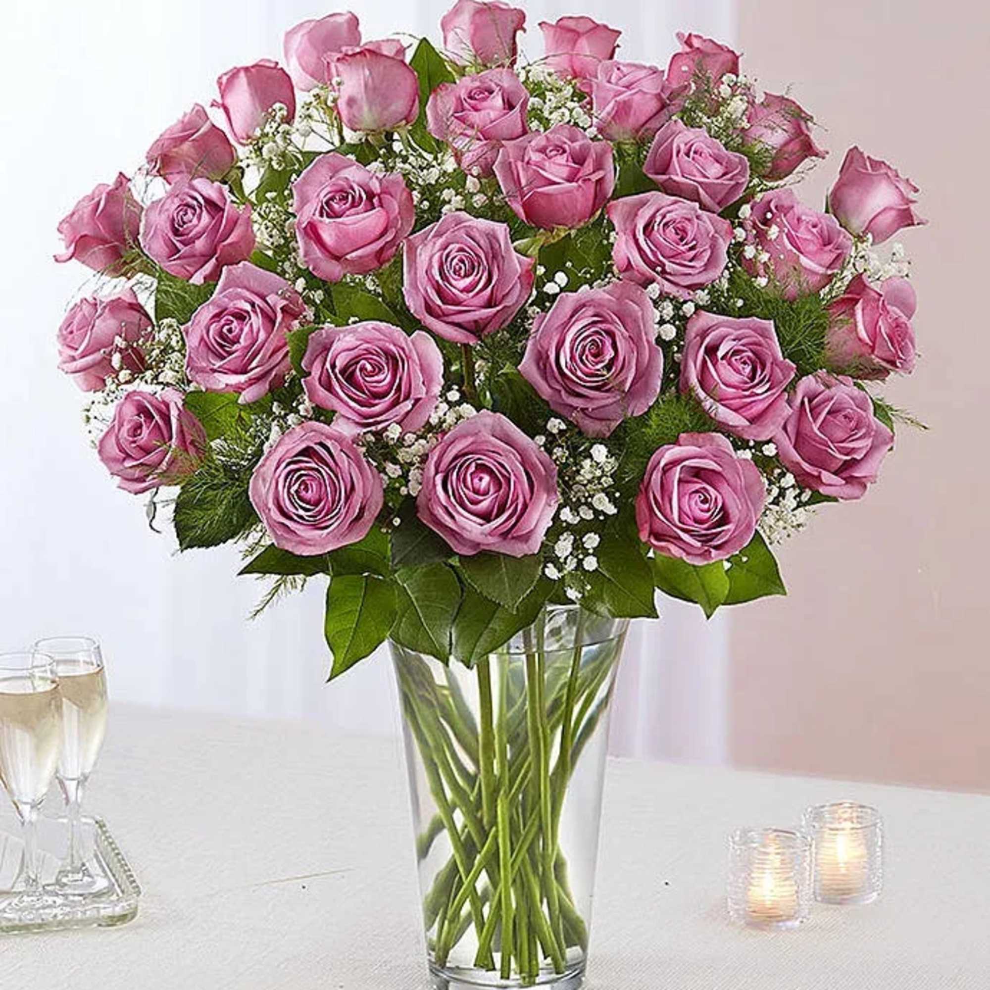 Pink roses arranged in a clear glass vase with baby's breath