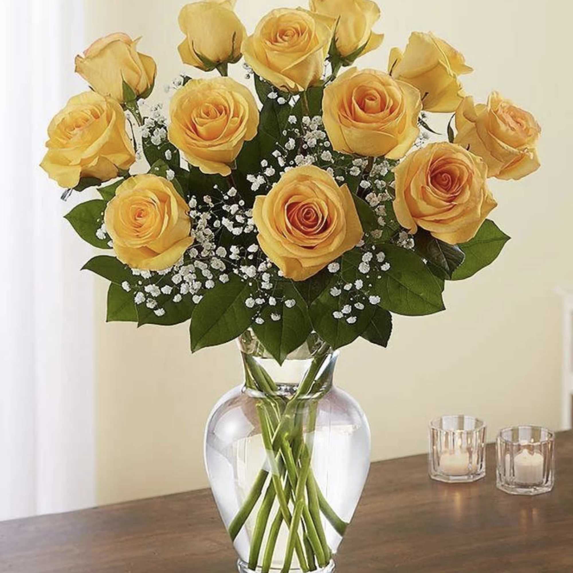 Yellow roses arranged in a clear glass vase with baby's breath