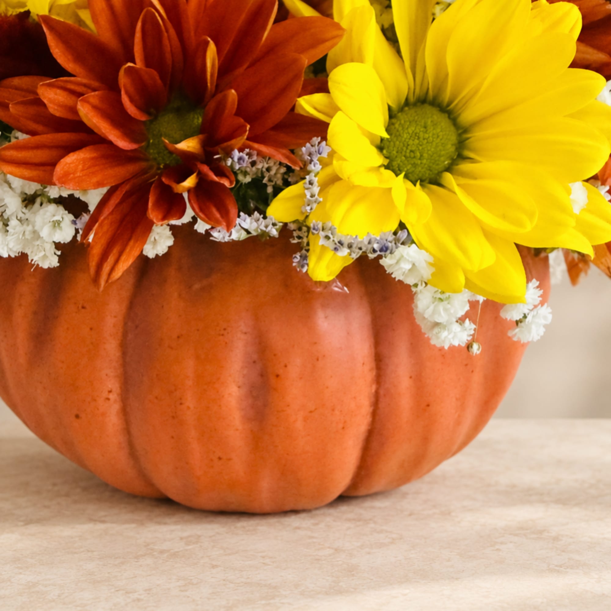 Pumpkin centerpiece with yellow and rust daisies