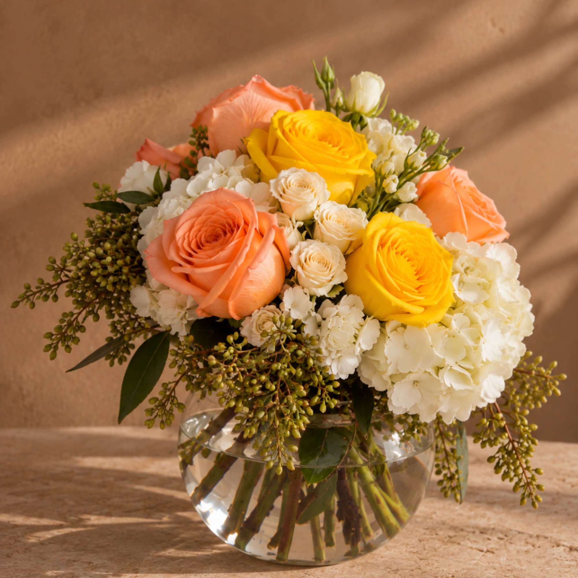 Bouquet of peach and yellow roses in a clear glass vase