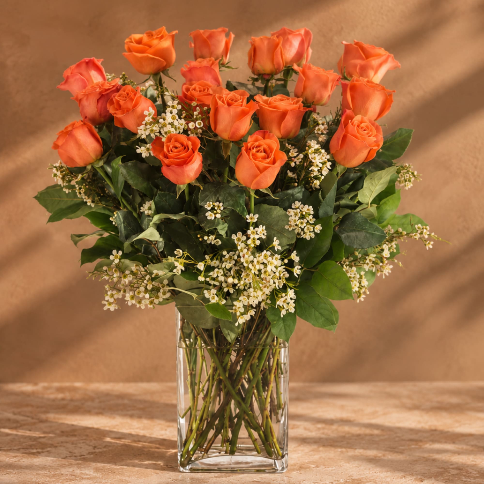 Orange roses in a clear glass vase with small white filler flowers, photo 3 of 4