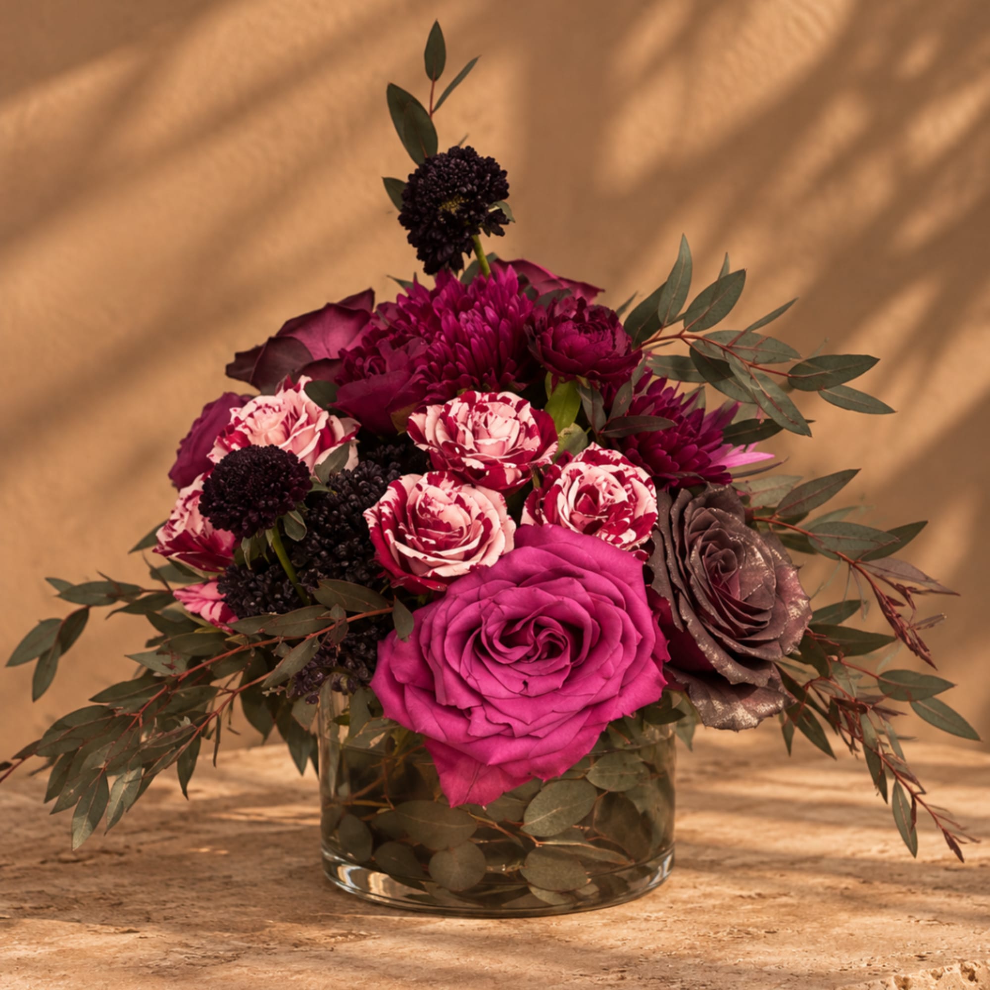 Magenta and burgundy floral arrangement in a clear glass vase