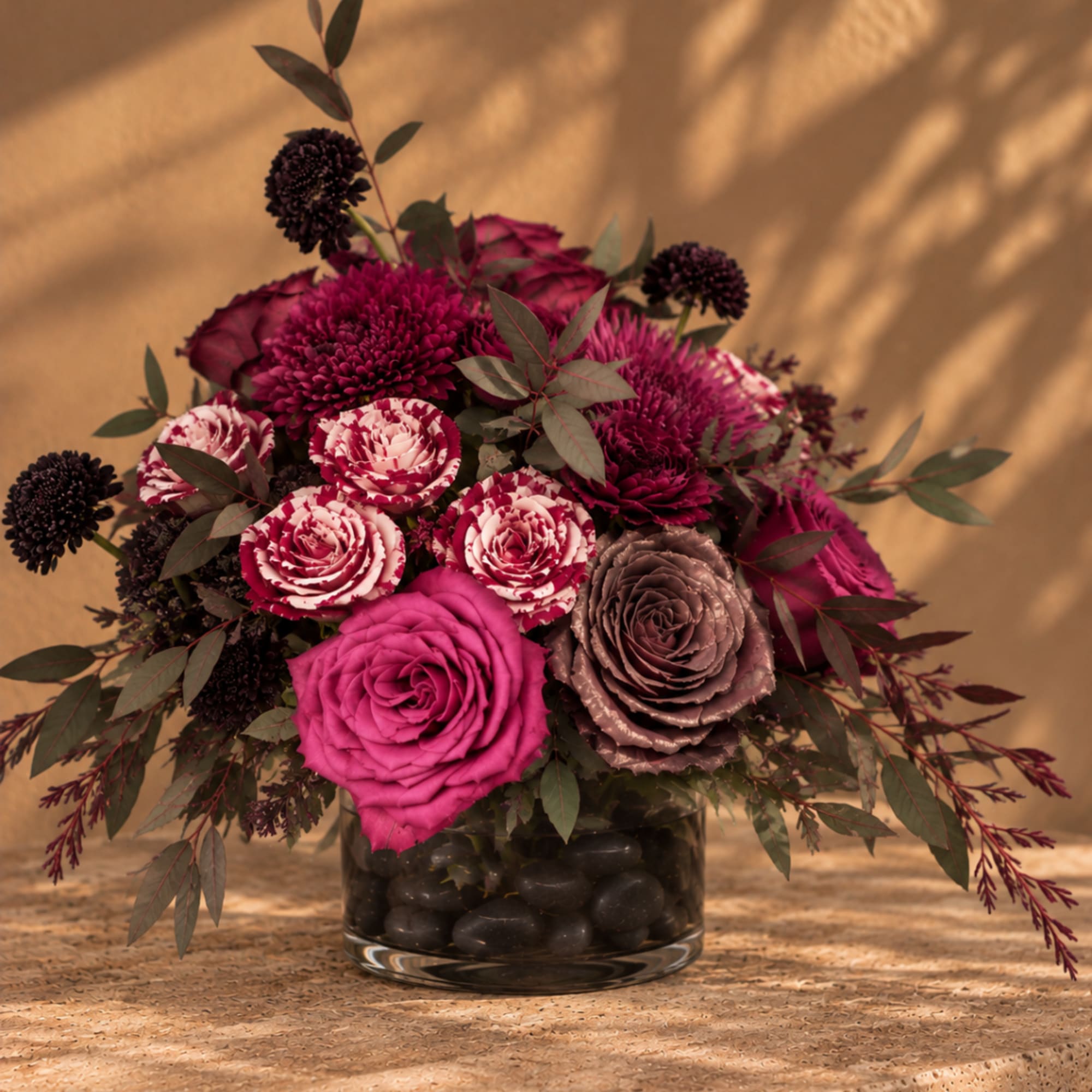 Pink and burgundy roses in a glass vase with dark filler flowers