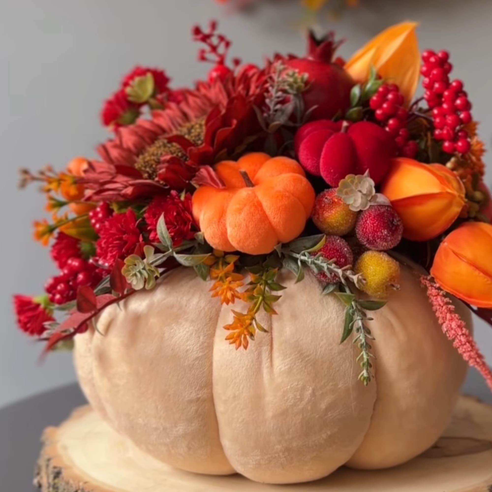 Pumpkin-shaped centerpiece with red and orange flowers and berries