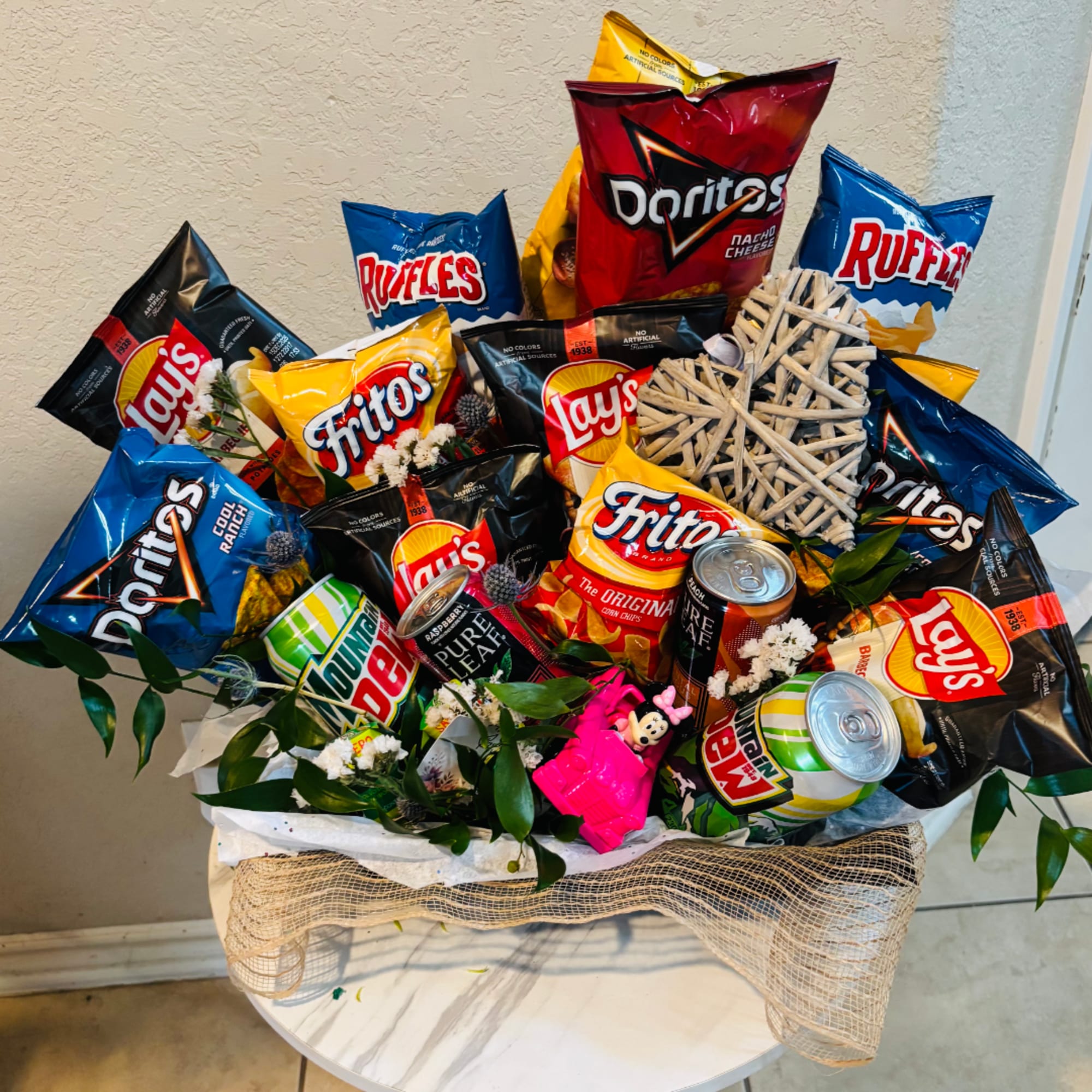 Snack bouquet with assorted chip bags and soda cans in a basket