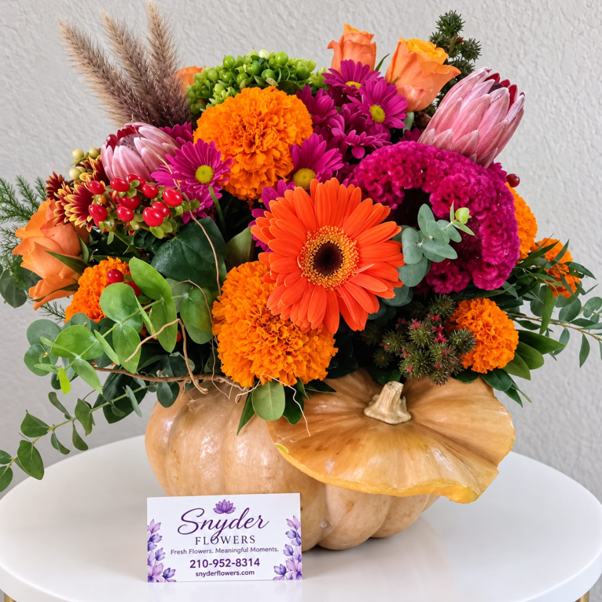 Autumn floral arrangement in a pumpkin container with orange and magenta blooms