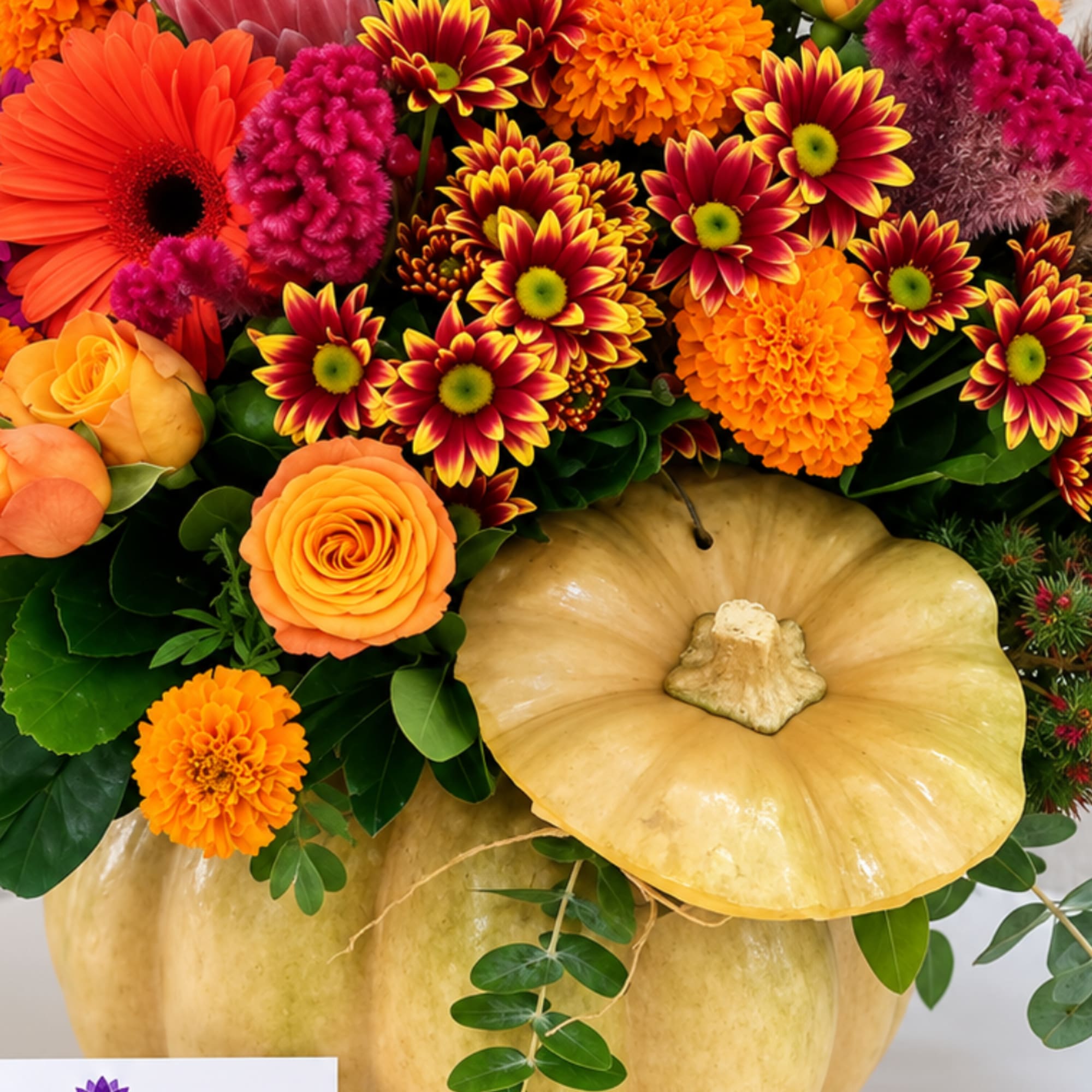 Orange and magenta flowers arranged in a pumpkin container