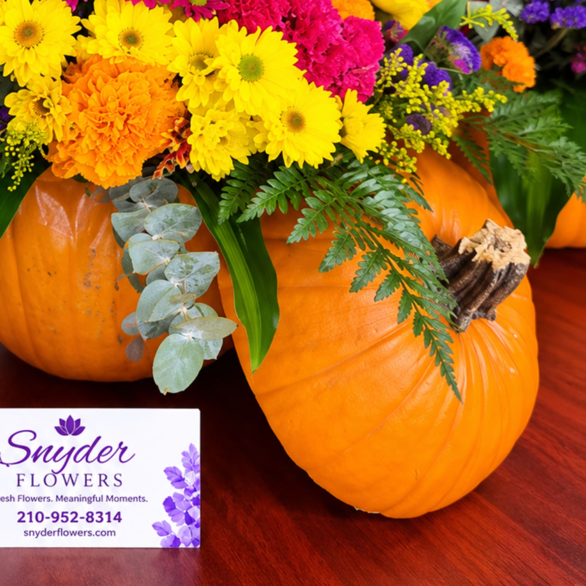 Pumpkins topped with a colorful fall flower arrangement