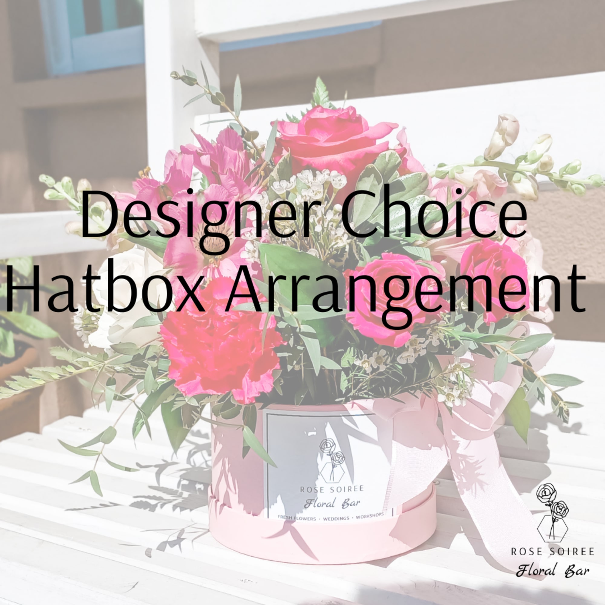 Round pink hatbox filled with bright pink and white flowers and a bow on a slatted surface