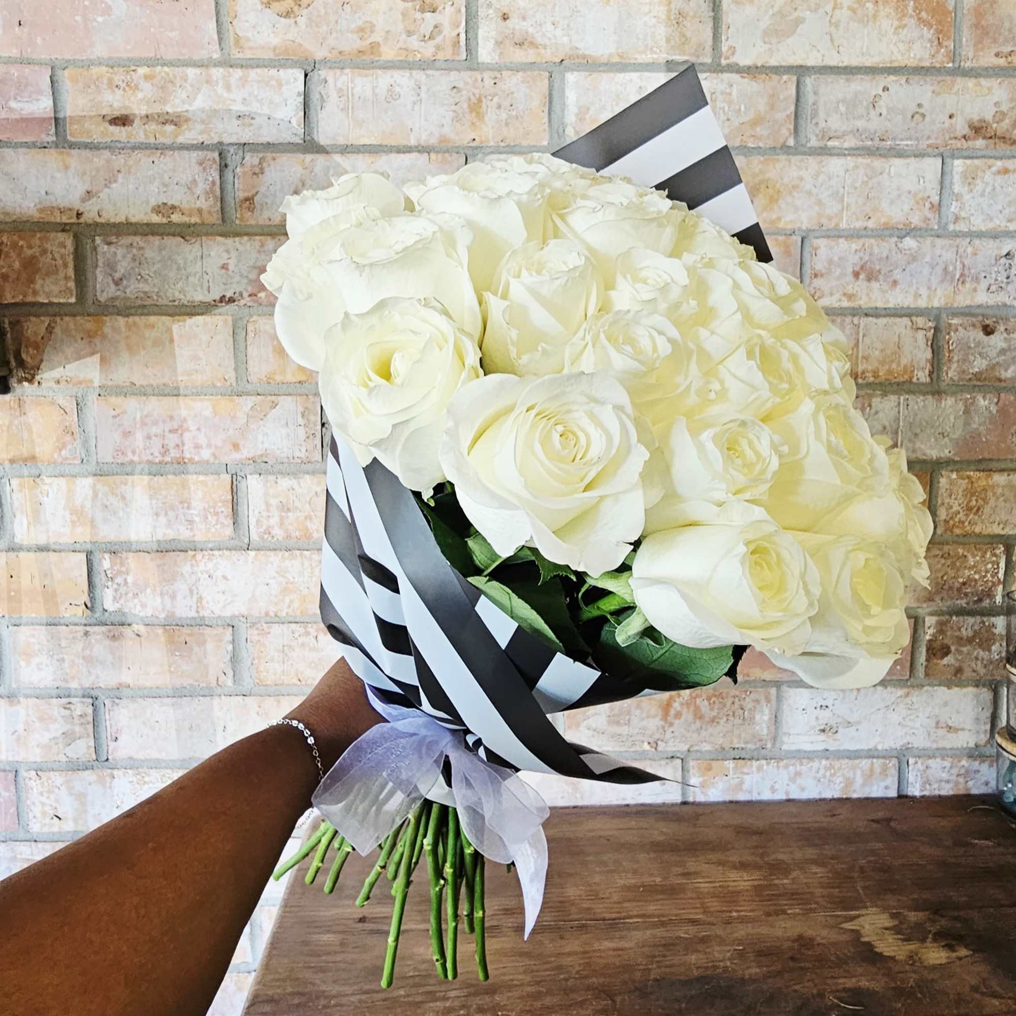 Bouquet of white roses wrapped in black-and-white paper with a ribbon