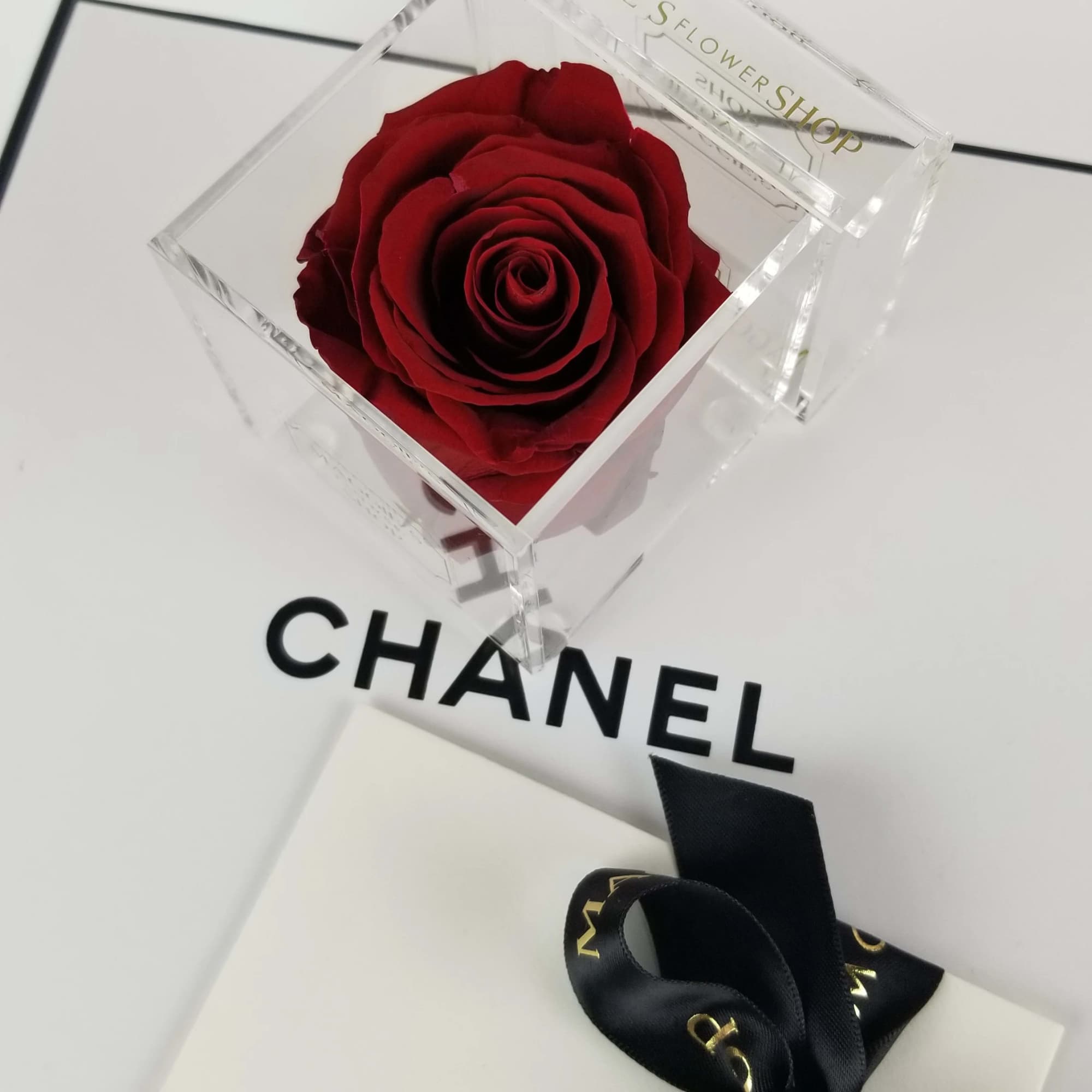 Single red rose in a clear acrylic box with a black ribbon-tied gift box