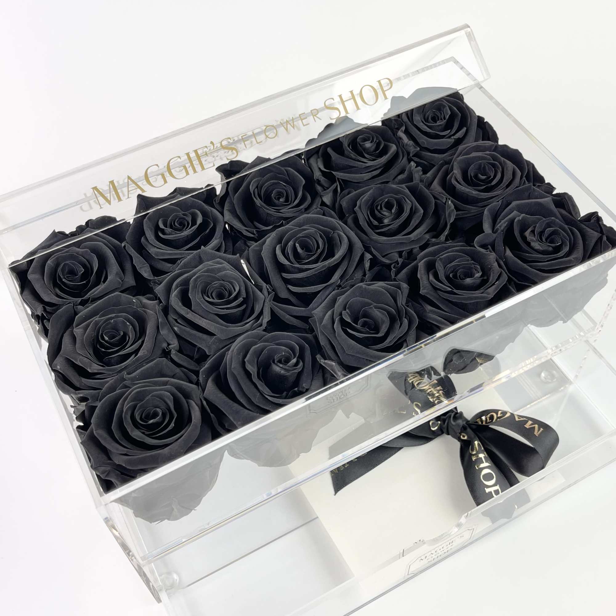 Black roses arranged in a clear gift box with a ribbon