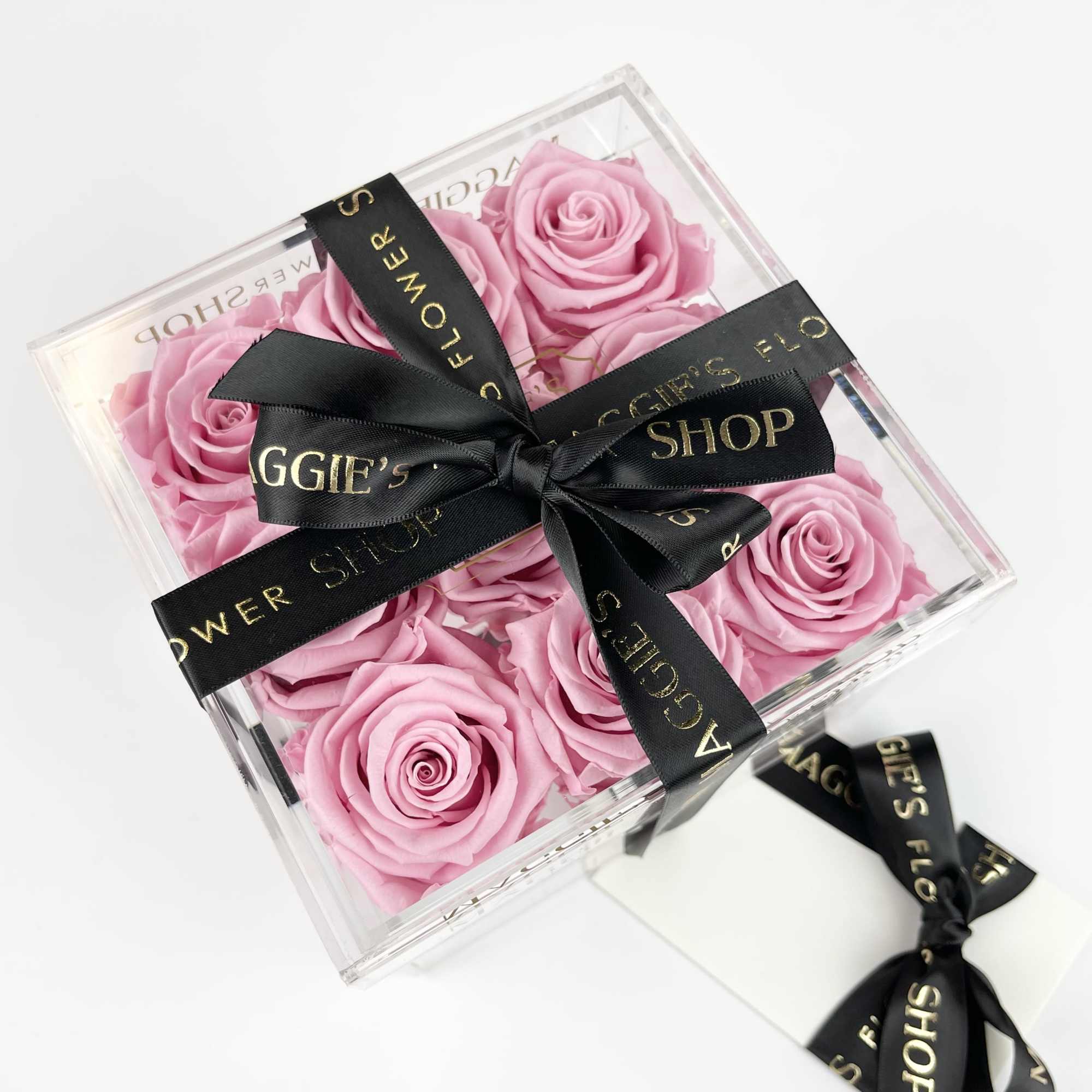 Pink roses in a clear gift box tied with a black ribbon