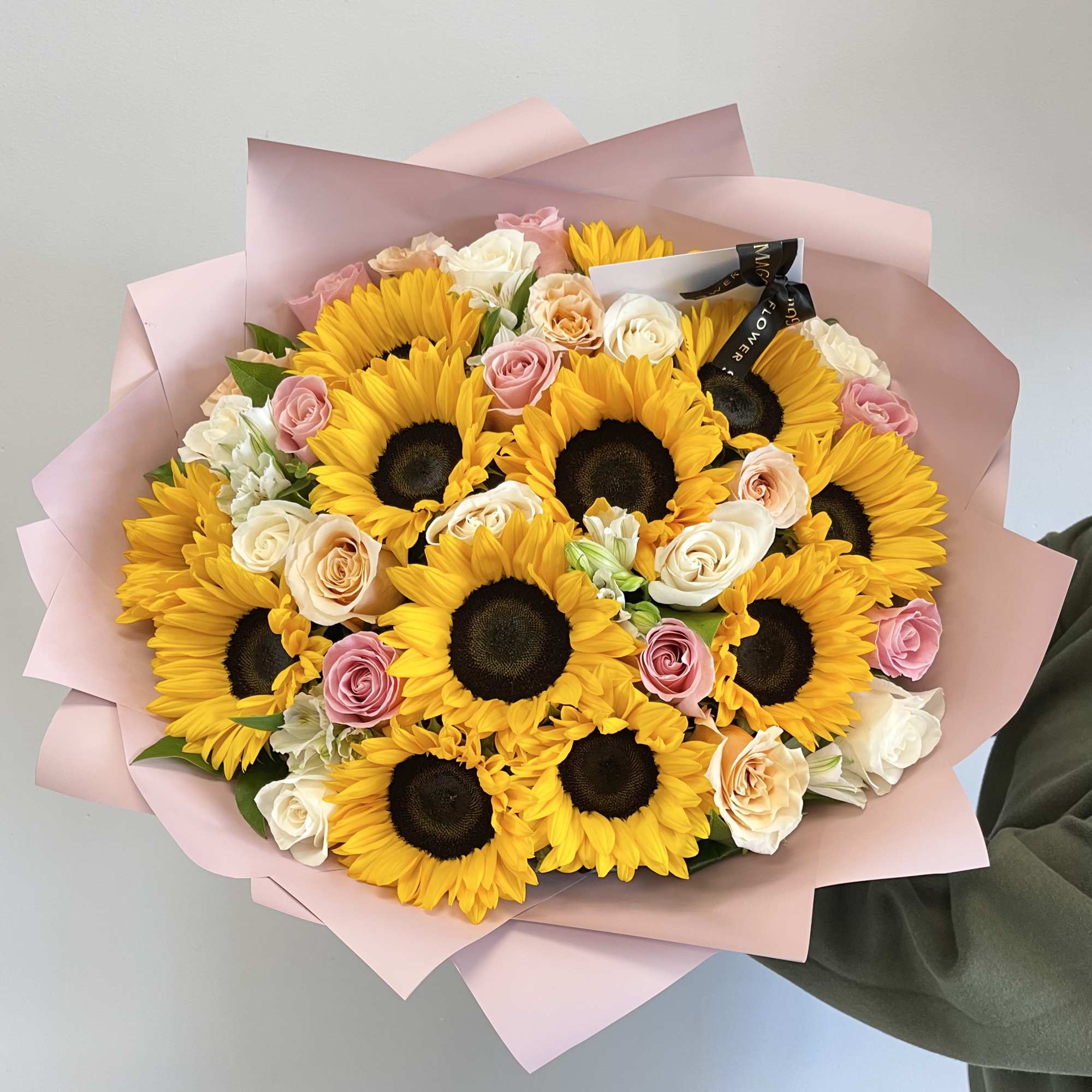 Bouquet of sunflowers and pastel roses wrapped in pink paper
