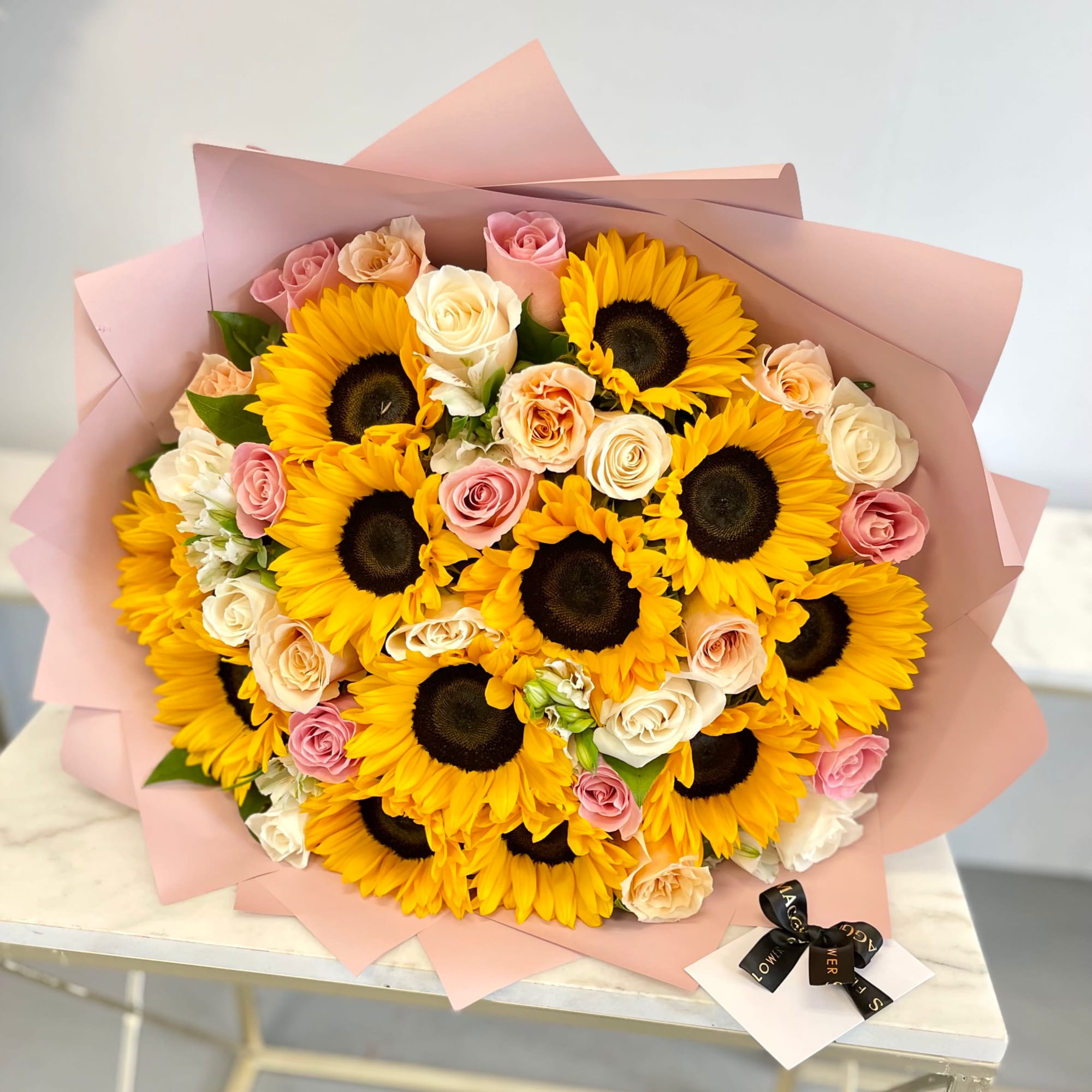 Bouquet of sunflowers and pastel roses wrapped in pink paper, photo 2 of 2