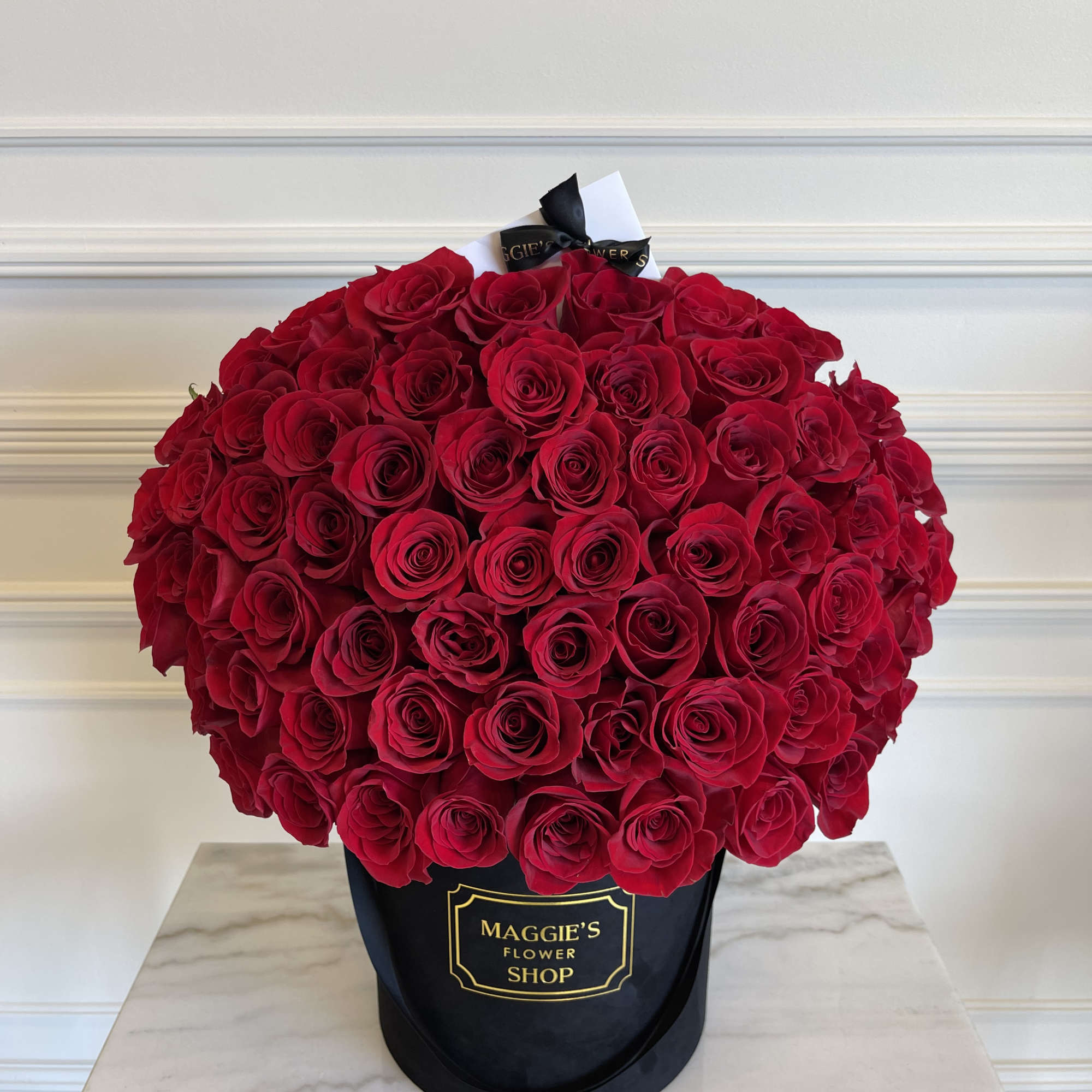 Large bouquet of red roses in a black hatbox