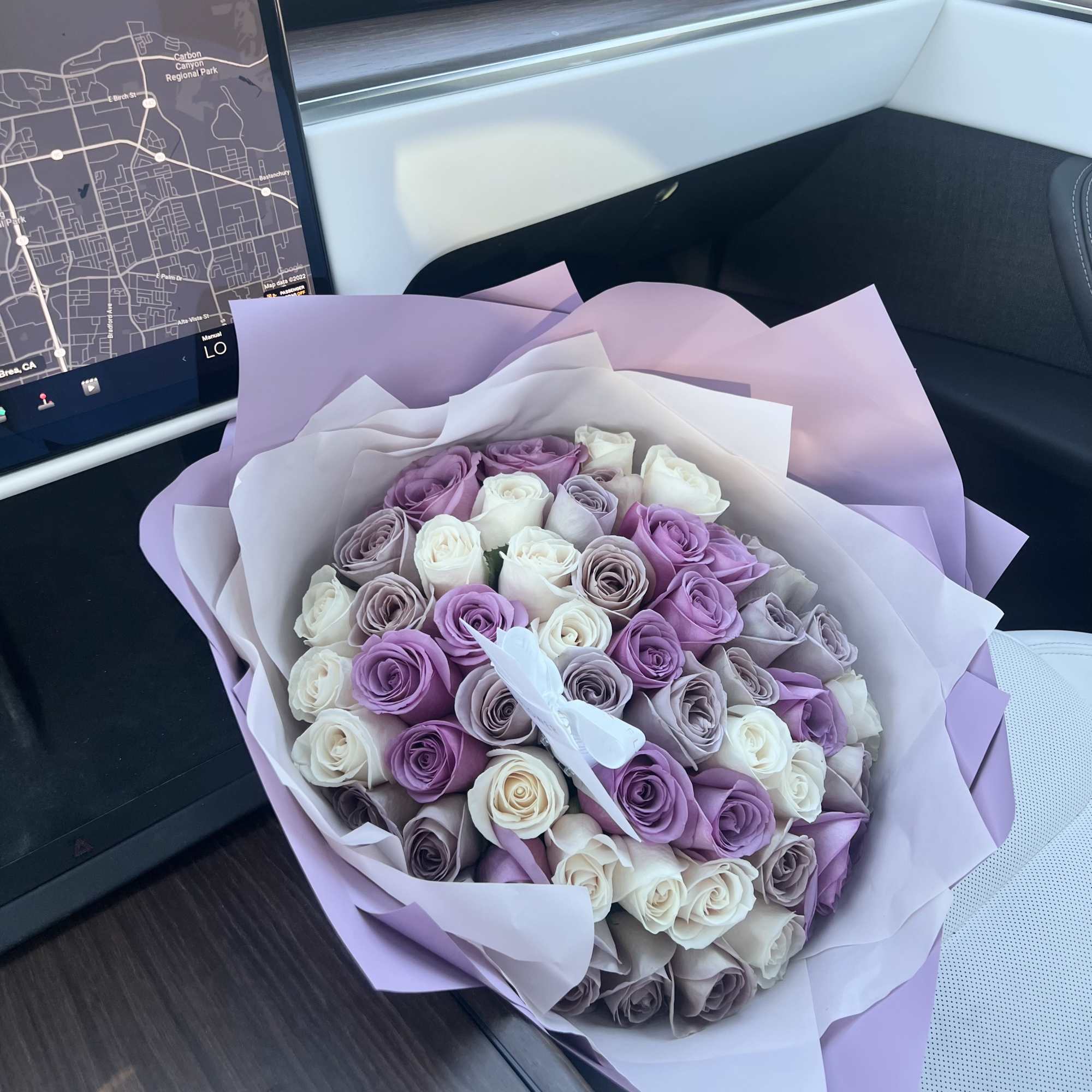 Bouquet of lavender, blush, and white roses wrapped in pastel paper