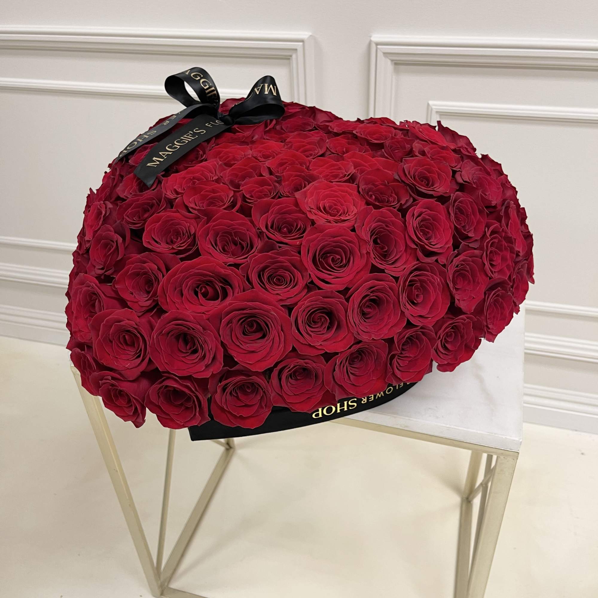 Large dome arrangement of red roses with a black ribbon bow
