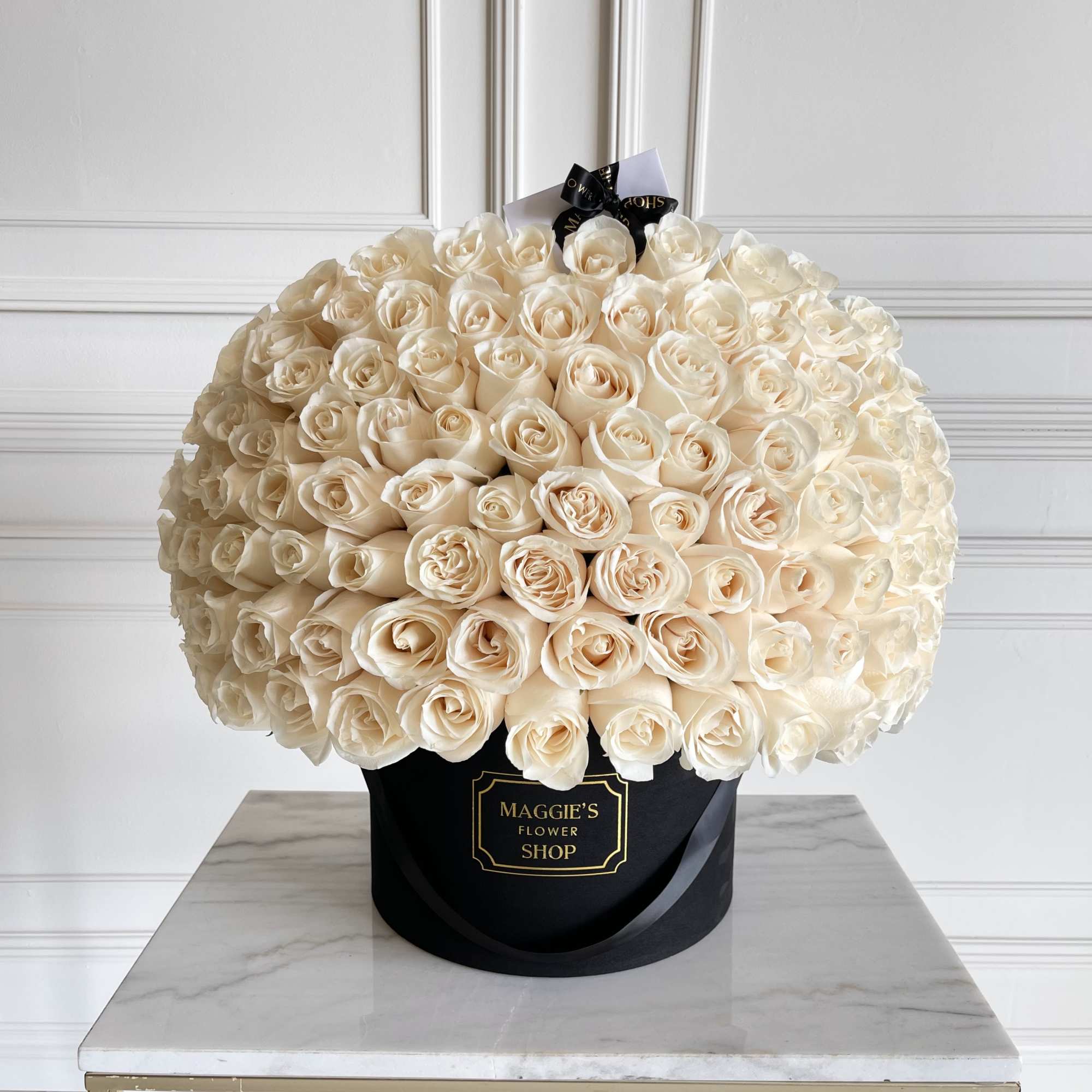 Large bouquet of cream roses in a black hatbox