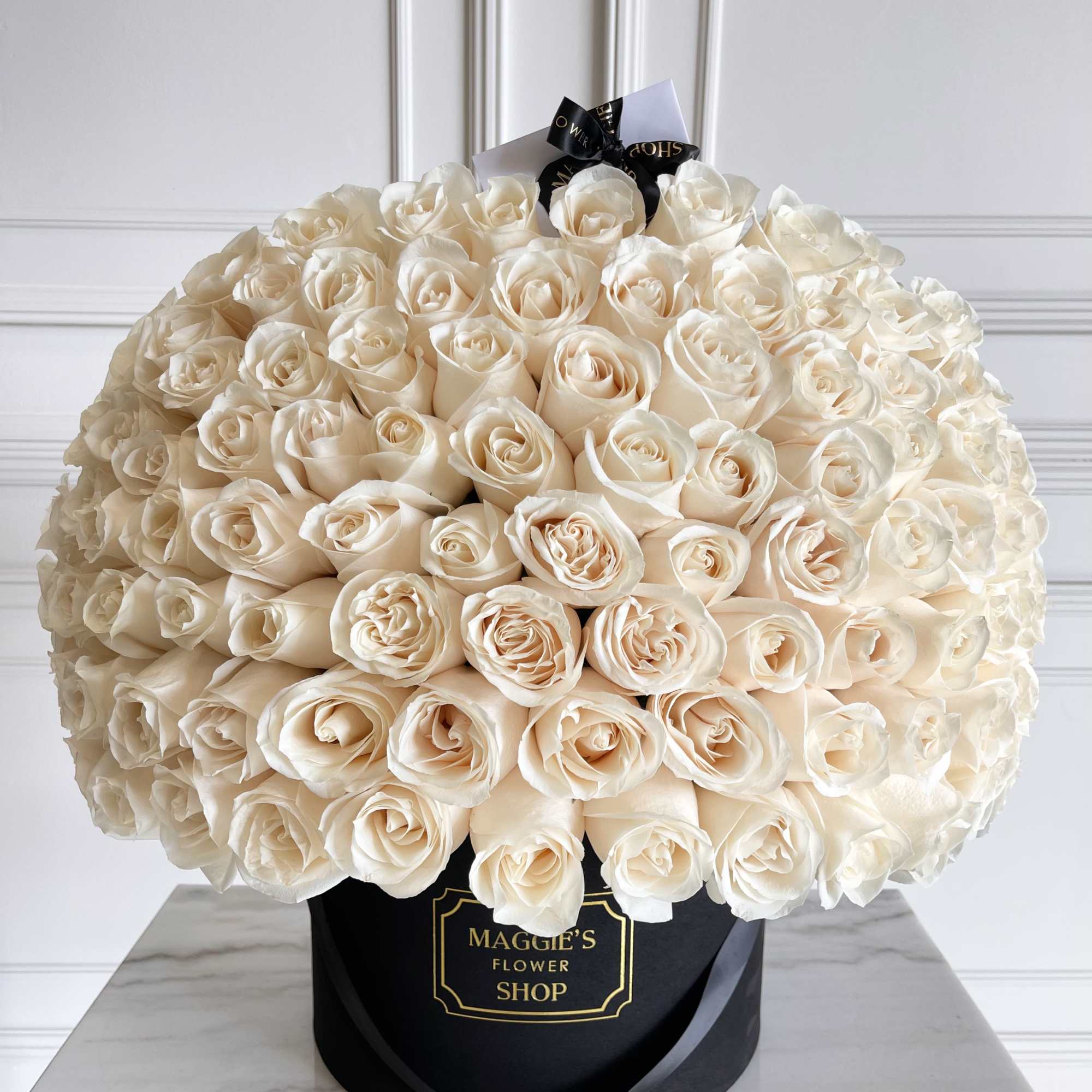 Large bouquet of cream roses in a black hat box