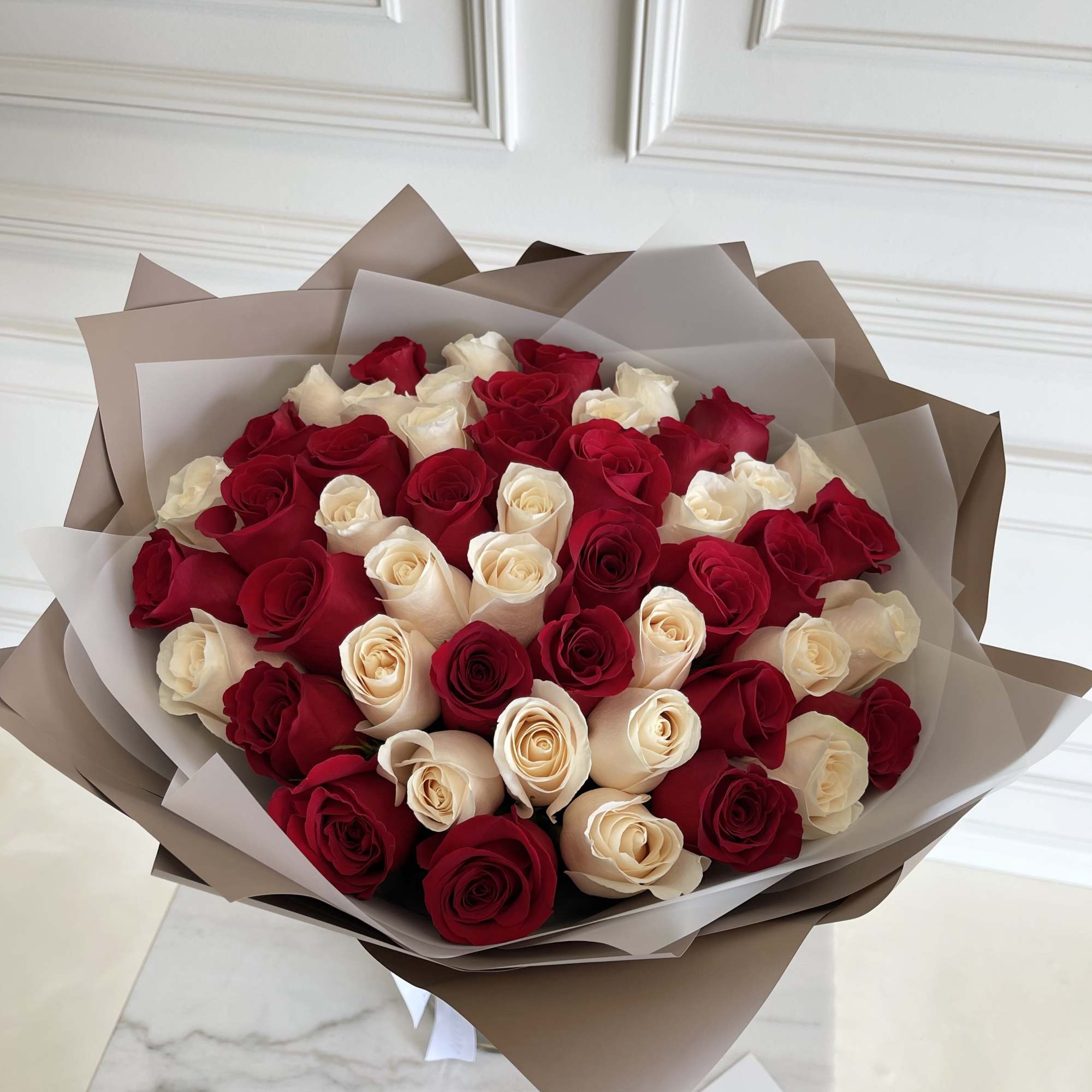 Bouquet of red and cream roses wrapped in brown paper