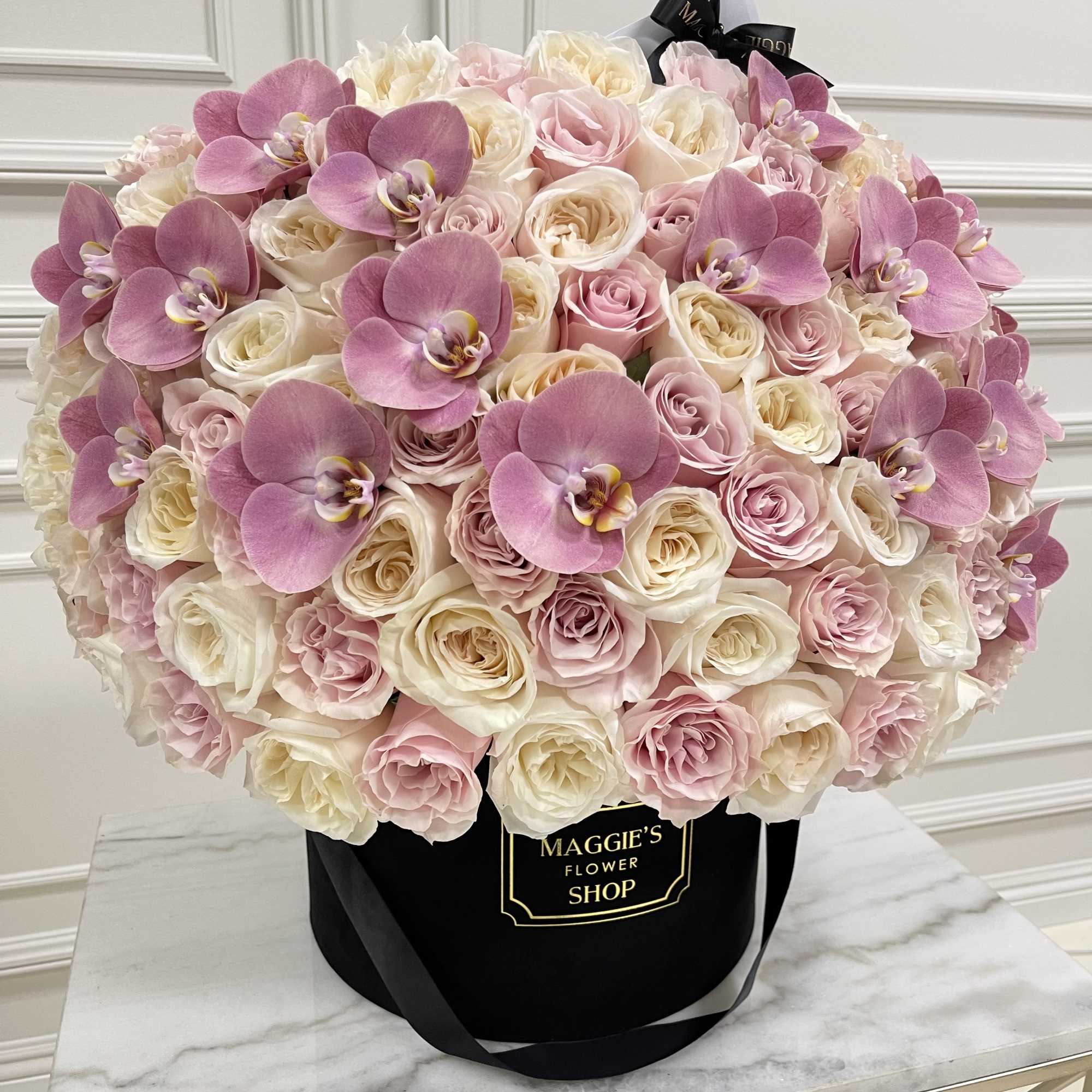Pink and white rose bouquet with orchid blooms in a black hat box