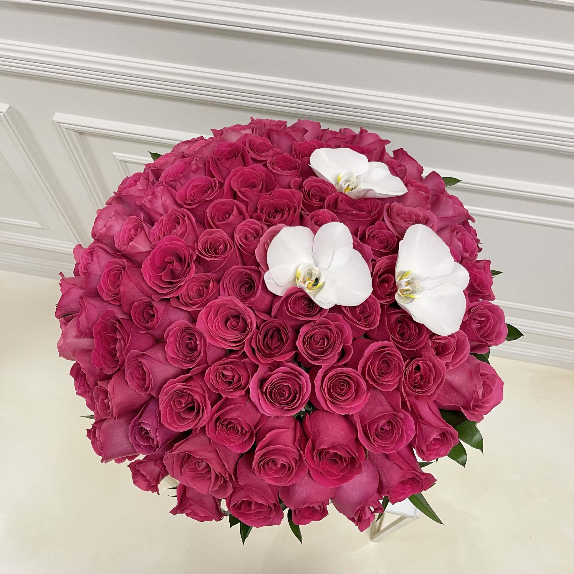 Round bouquet of hot pink roses with three white orchids