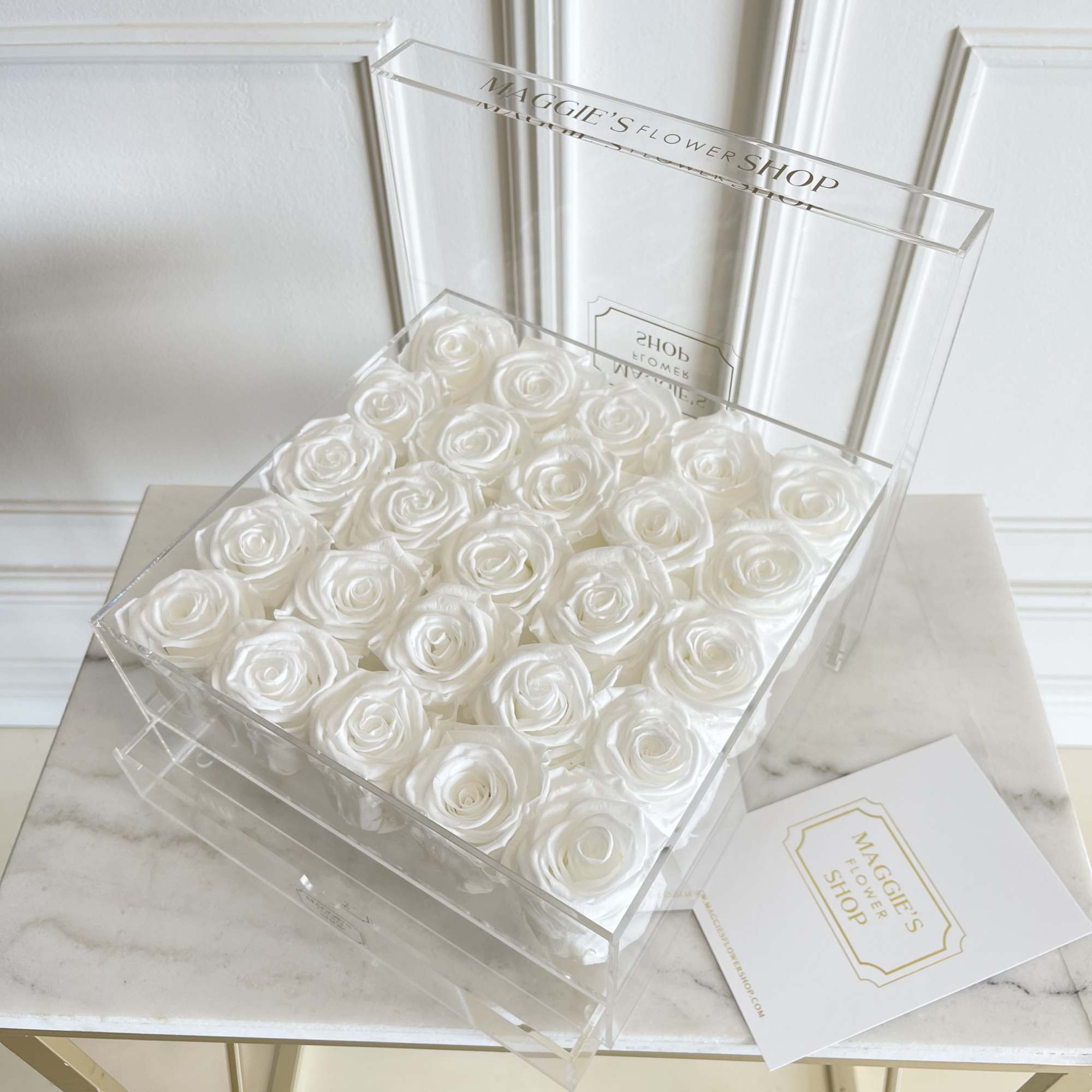 Clear box filled with white roses on a marble table