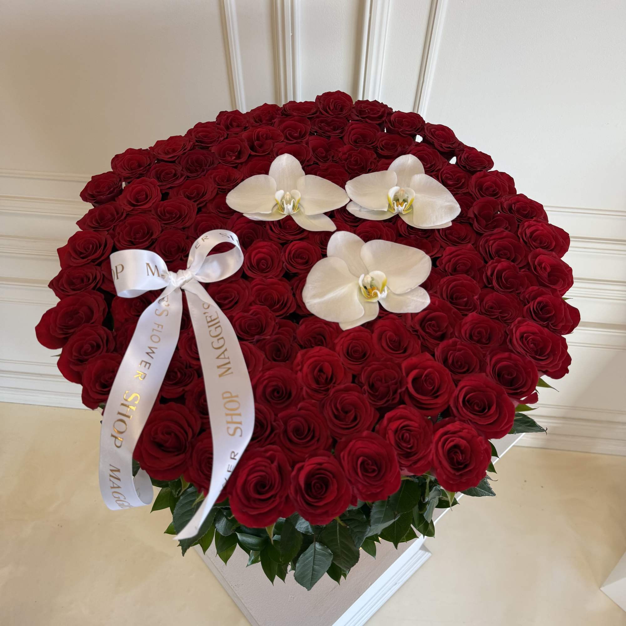 Large round arrangement of red roses with white orchids and a ribbon, photo 2 of 2
