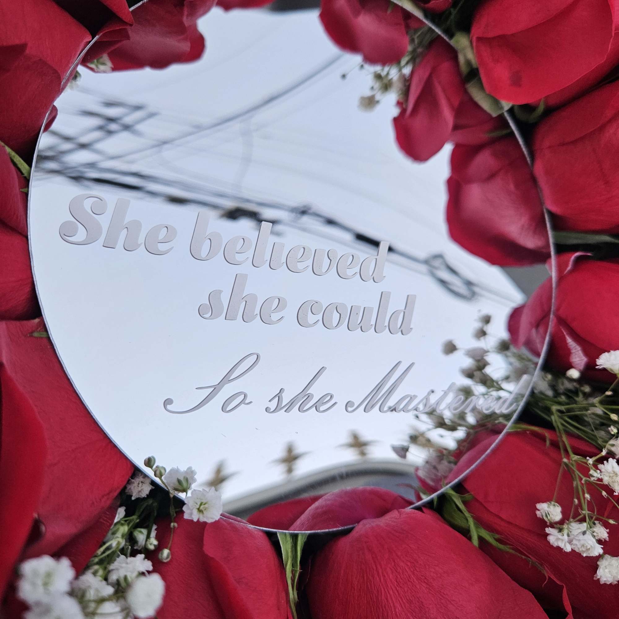A bold circle of deep red roses arranged around a mirrored center, photo 2 of 3