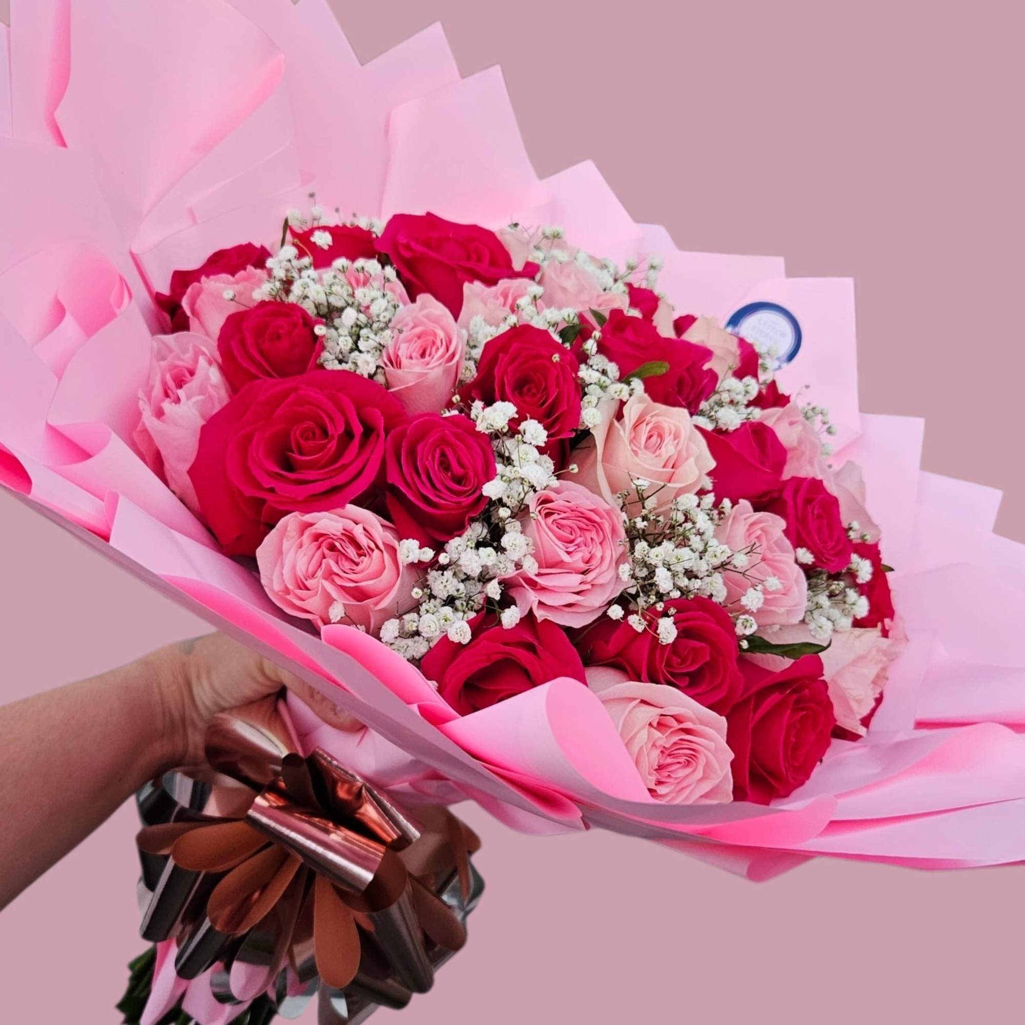 A lush, hand-tied bouquet of tightly packed pink and deep red roses, photo 2 of 2