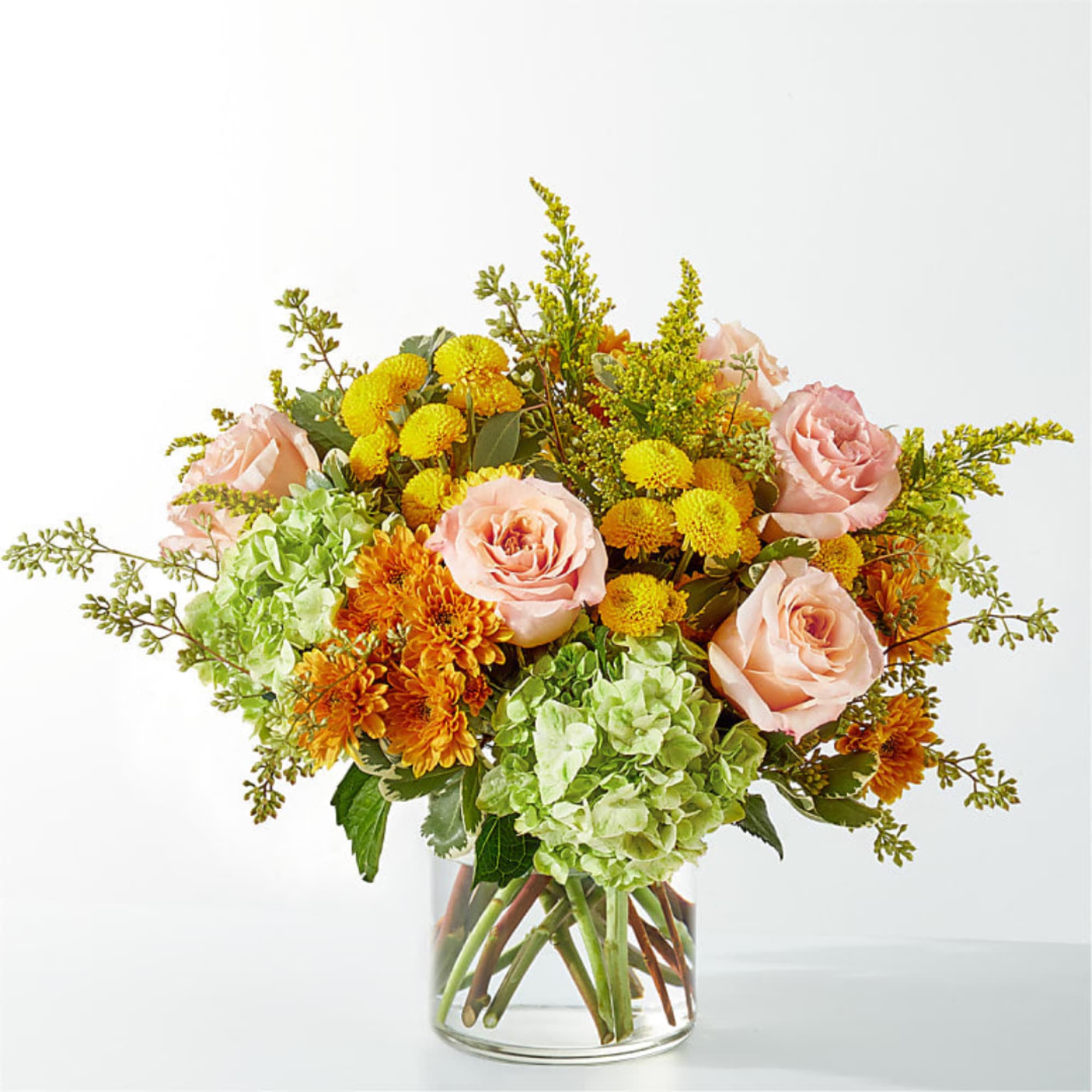 Bouquet of pink roses, green hydrangeas, and yellow-orange mums in a clear glass vase