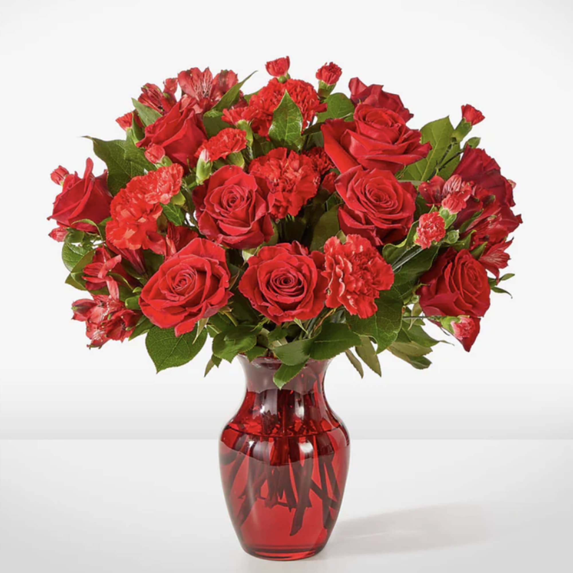 Red roses and carnations in a red glass vase